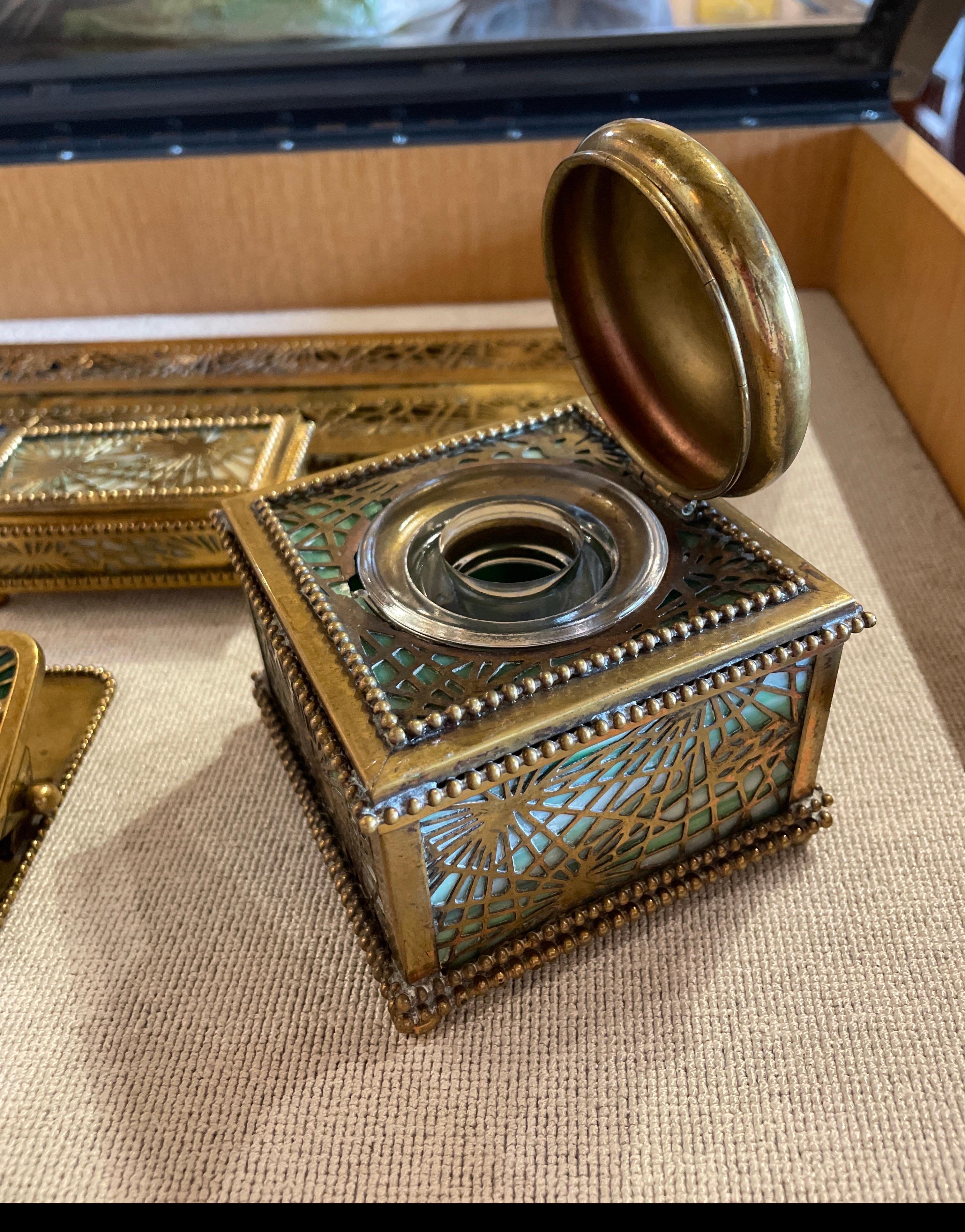 Ein außergewöhnliches siebenteiliges Schreibtischset der Tiffany Studios New York, das um das frühe 20. Jahrhundert in dem ikonischen Pine Needle Pattern gefertigt wurde. Dieses detailreiche Ensemble mit seinen warmen Bronzedorierungen und den