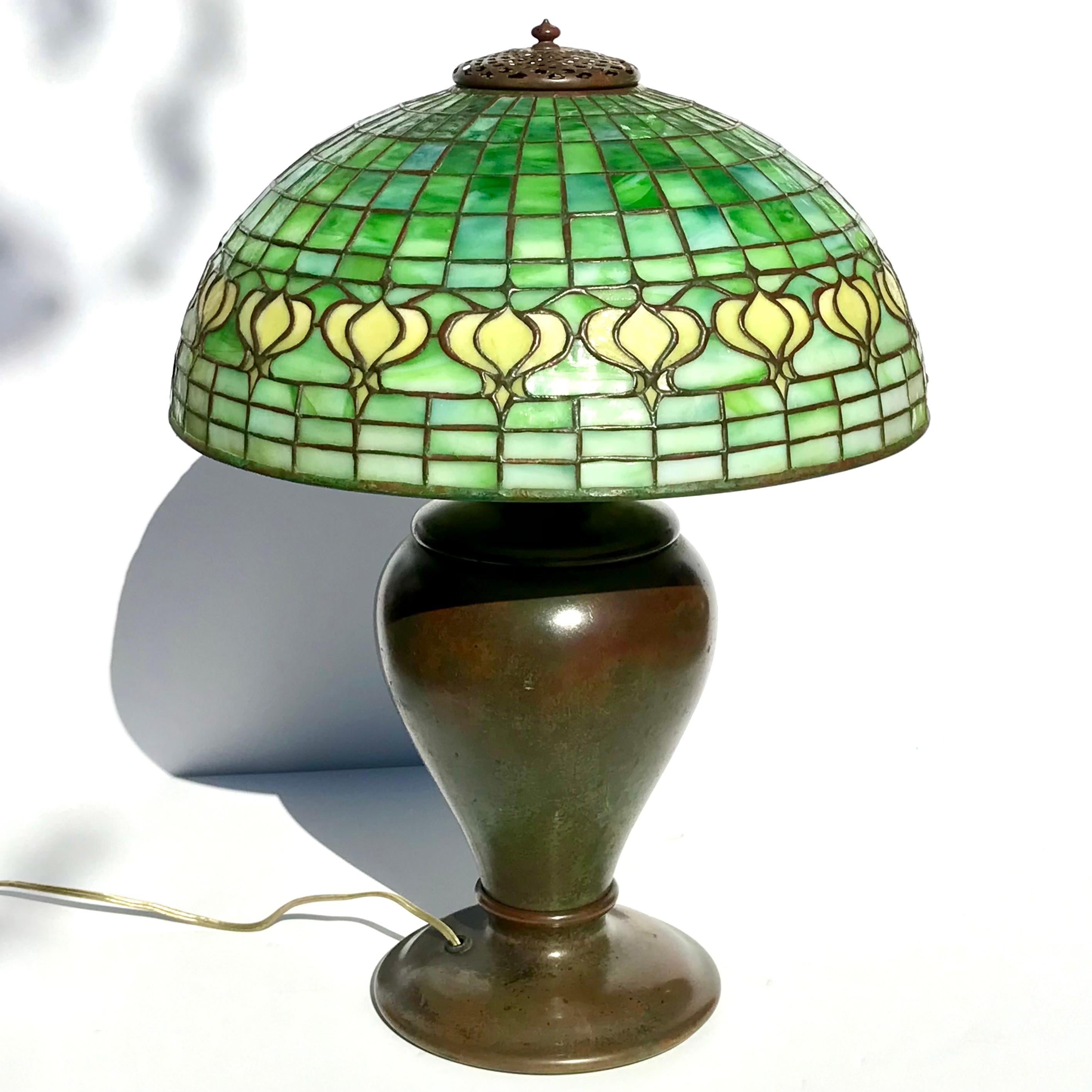 Tiffany Studios Pomegranate Leaded Glass and Patinated Bronze Table Lamp. A beautiful Tiffany Studios ensemble with a rare and early patinated bronze base with original Bryant sockets, paddles and heat cap. The Pomegranate Shade with slag and