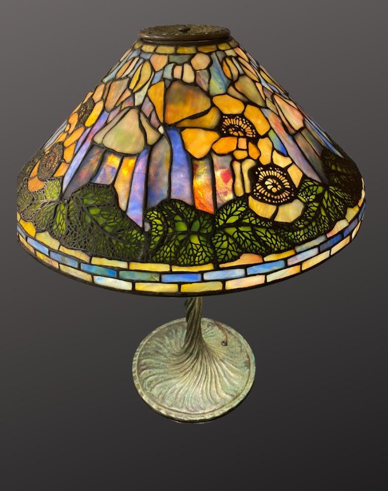 The “Pond Lily” table lamp, an exquisite piece from Tiffany Studios around 1905. It highlights the elegance of Tiffany's design, with a leaded glass shade shaped like pond lily petals and a twisted vine base in patinated bronze, embodying the