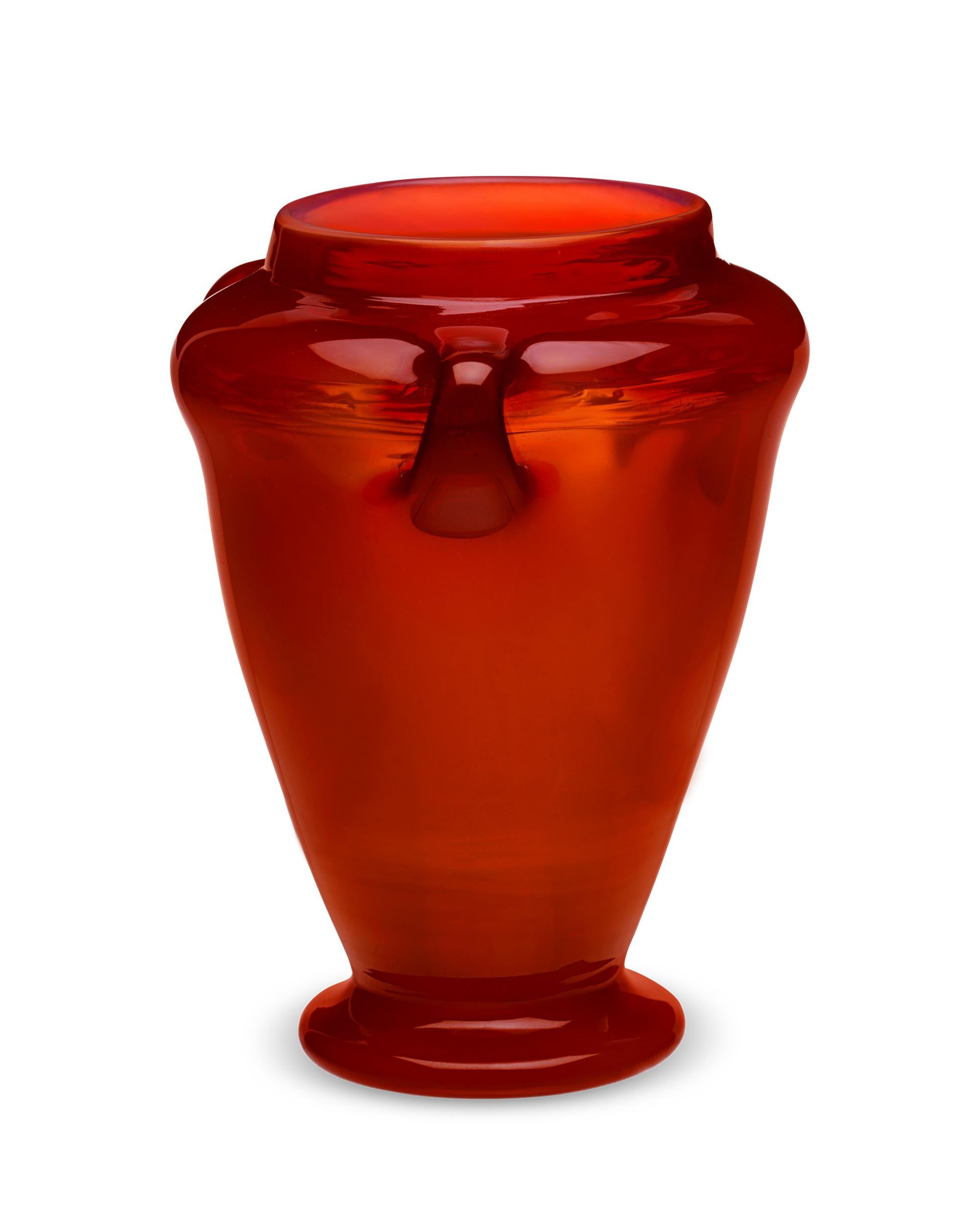 Crafted from a deep and vibrant red glass, this luminescent Favrile vase was made by the legendary Tiffany Studios. Of all the Favrile glass hues, red is the most elusive and difficult to find due to its high cost of production. A red Favrile vase