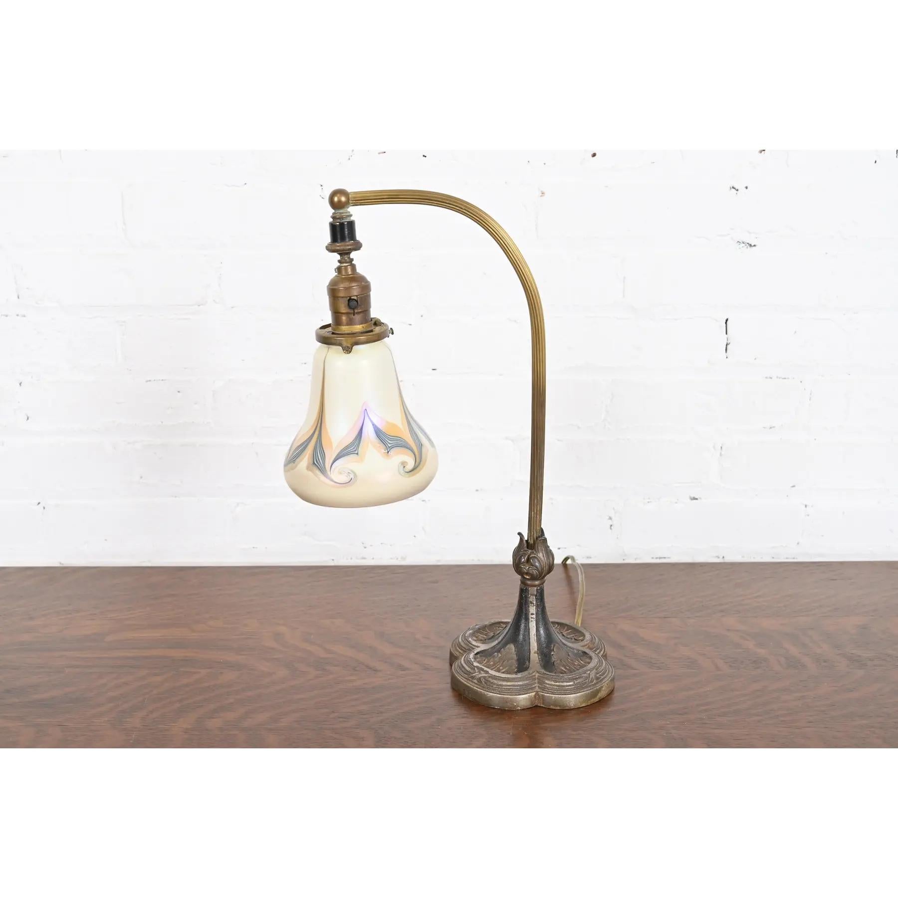 A gorgeous antique Art Deco or Art Nouveau period desk lamp or table lamp

In the manner of Tiffany Studios

USA, Circa 1930s

Cast iron base, with brass stem, and beautiful Favrile art glass shade by Quezal.

Measures: 5.5