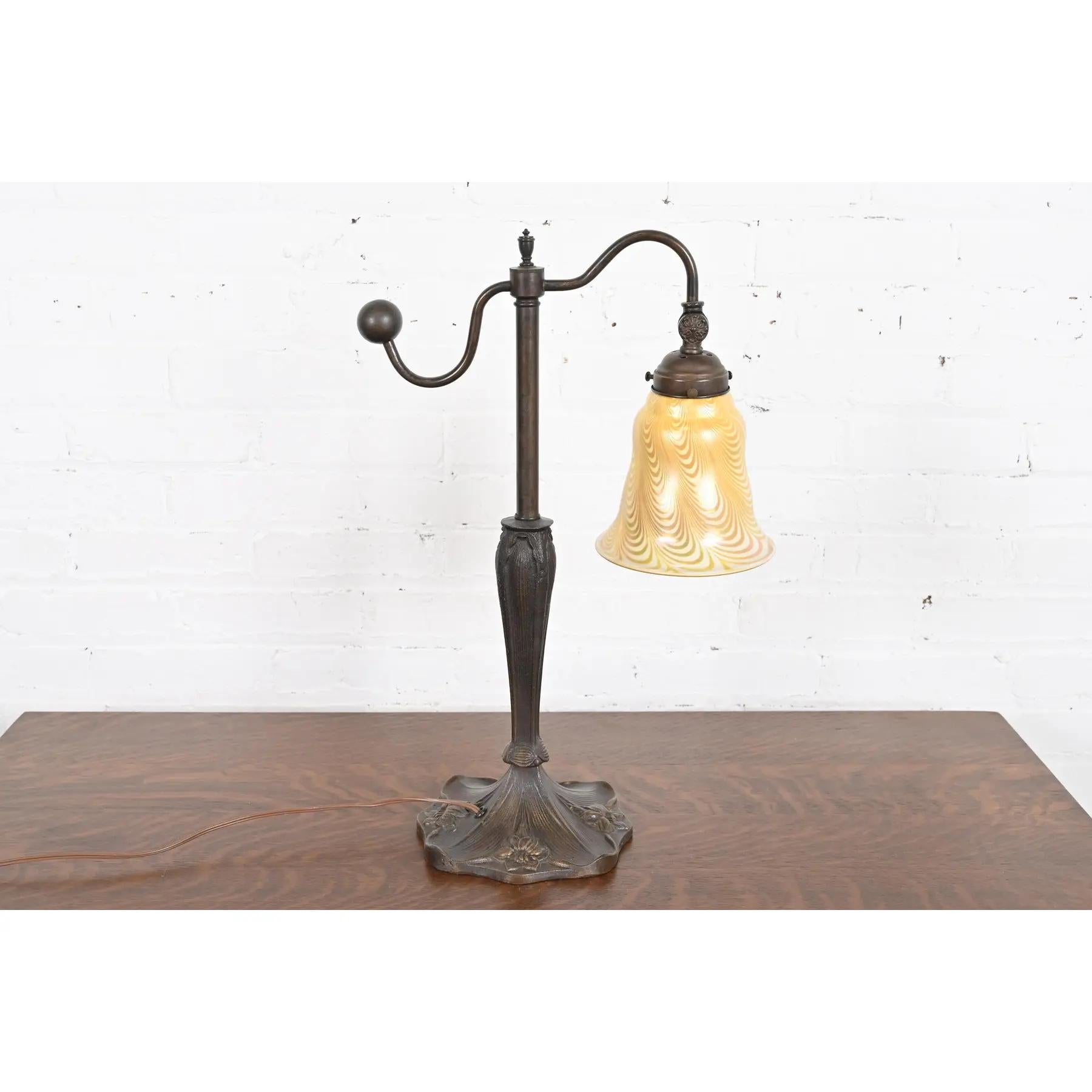 A gorgeous Art Nouveau or Arts & Crafts desk lamp or table lamp

In the manner of Tiffany Studios

USA, Circa Mid-20th Century

Bronze base, with gorgeous Louis Comfort Tiffany style iridescent art glass shade.

Measures: 12