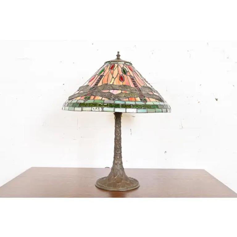 A gorgeous Arts & Crafts style stained glass table lamp

In the manner of Tiffany Studios

USA, Circa Late 20th Century

Bronze base, with jeweled stained glass dragonfly shade.

Measures: 20