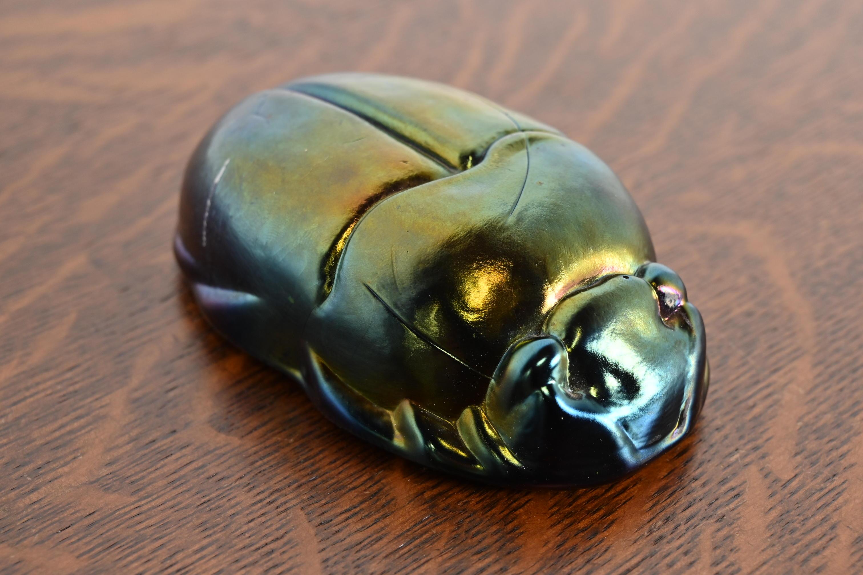 A gorgeous Arts & Crafts or Art Deco style iridescent favrile glass scarab paper weight

In the manner of Tiffany Studios

USA, 20th Century

Measures: 4.63