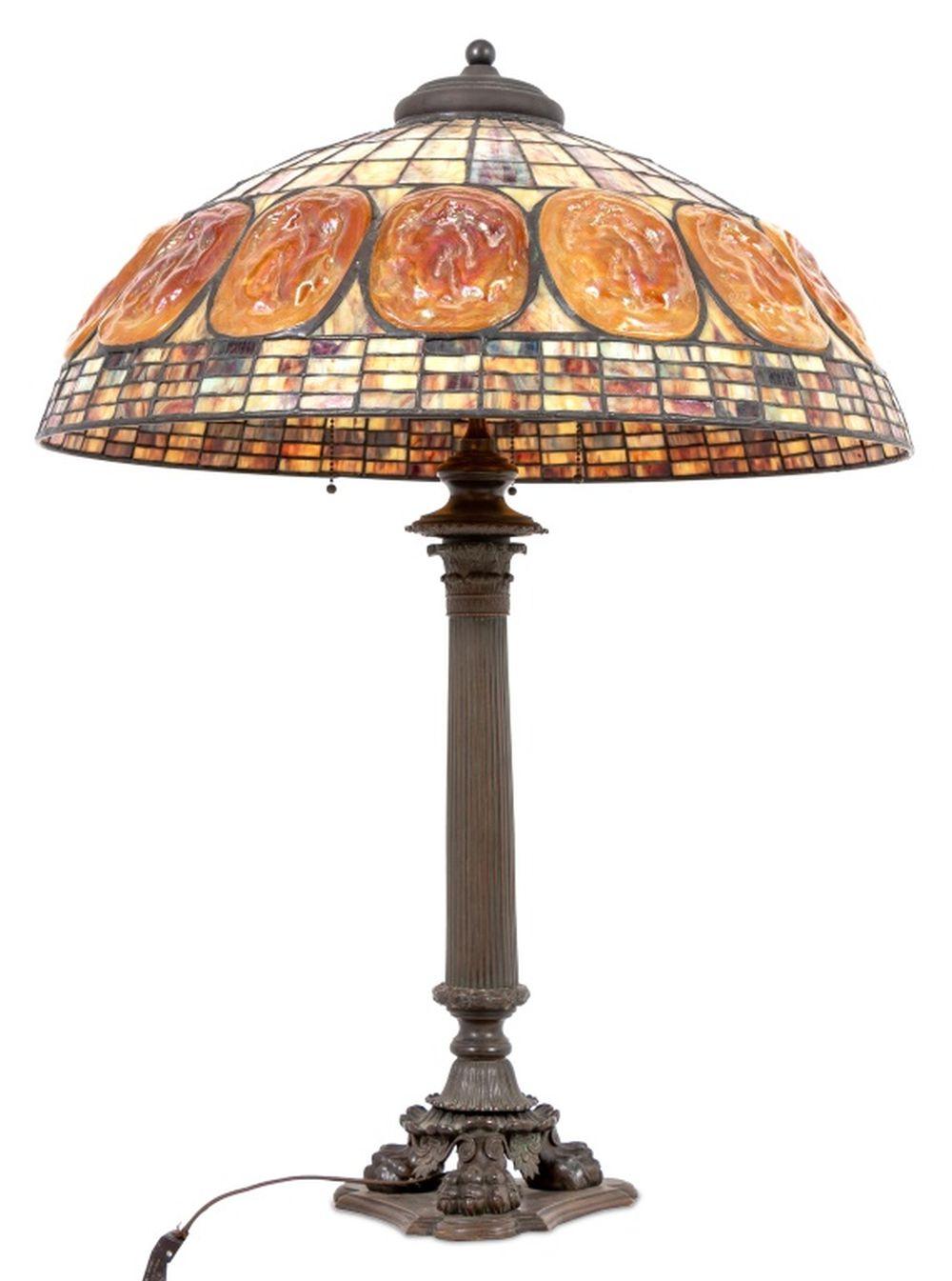 American Tiffany Studios Style Bronze and Slag Glass Table Lamp, early 20th century, with inset favrile turtleback tiles, the domed slag glass shade above a classical column, on a tripartite base with lion's paw feet. 36