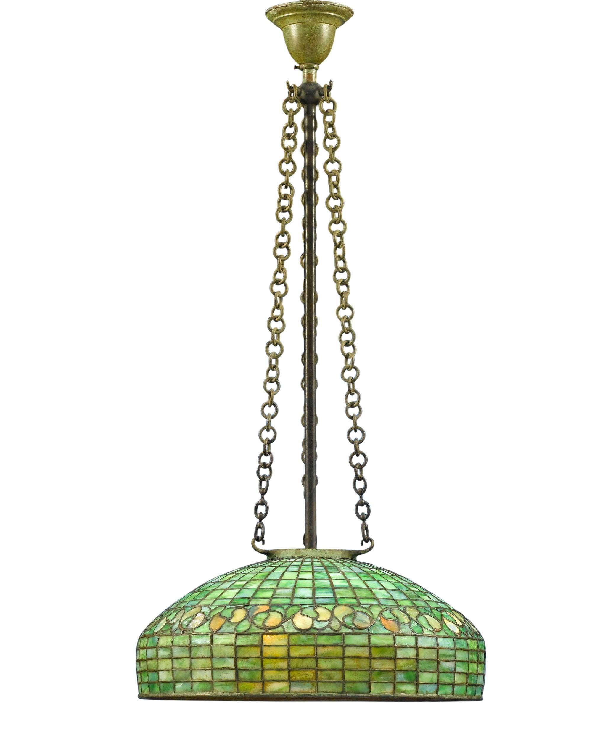 A beautiful Tiffany Studios hanging lamp in the Swirling Leaf pattern. This exceptional specimen is comprised of vivid green and golden yellow polychromatic glass arranged in what is considered to be one of the first patterns in Tiffany's