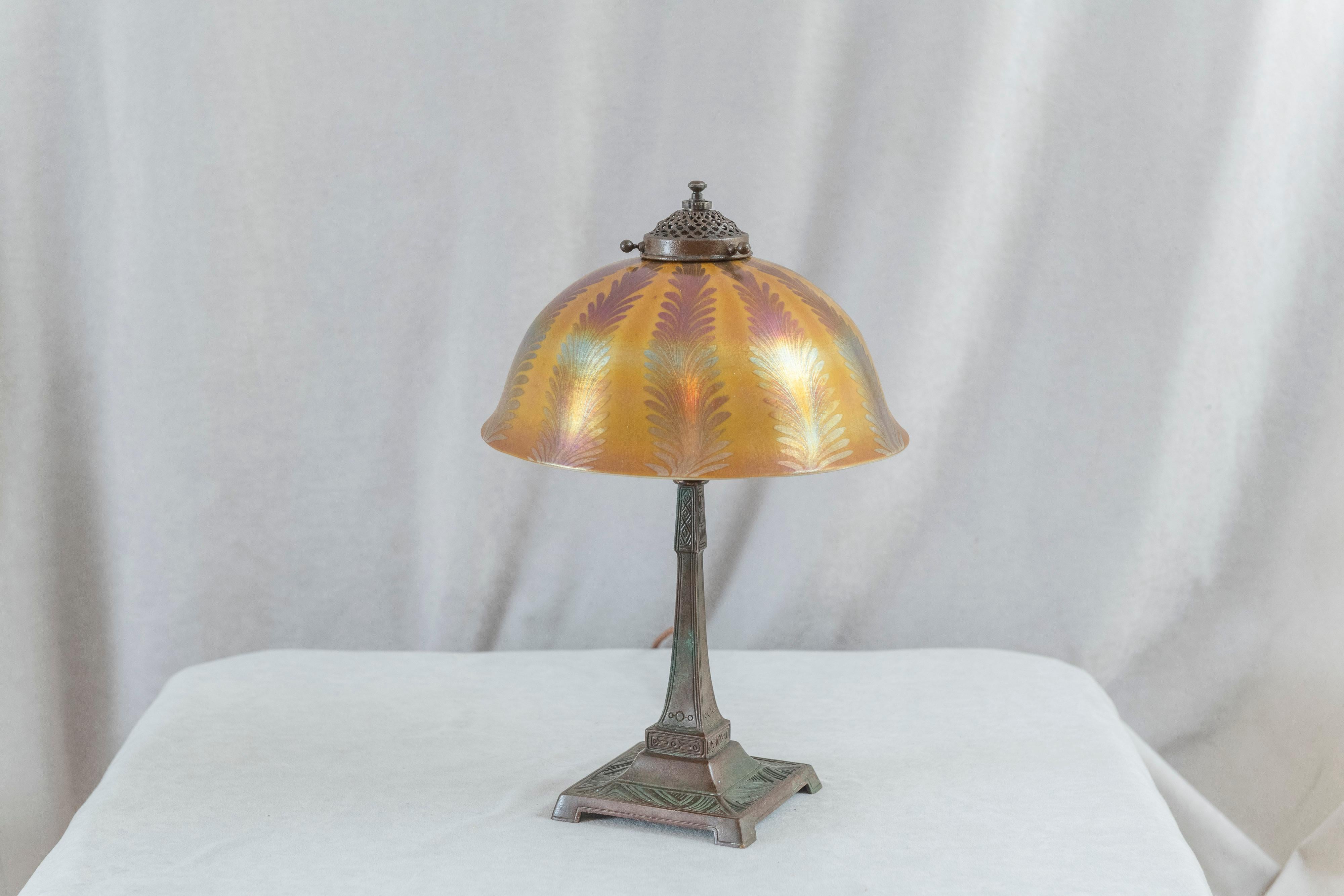  This lovely little Tiffany lamp can be put almost anywhere in your home. The  bronze base has a rich warm brown patina. The hand blown shade is beautiful and colorful. White lined keeping an opaque look and so the lightbulb is not visible. The