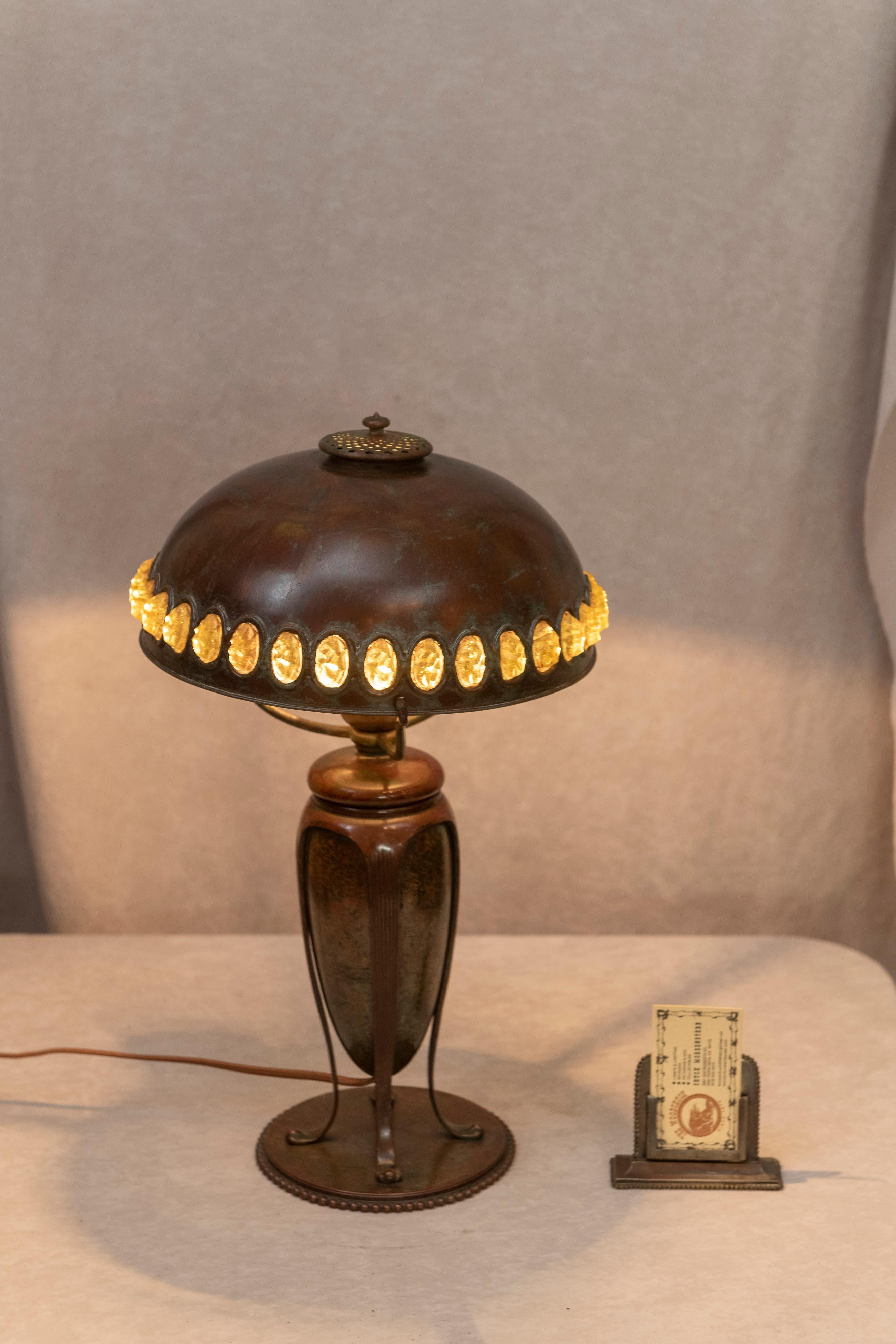 This very handsome lamp was done by the master lamp maker, Tiffany Studios. Rich brown patina and exotic jewels in the shade, and all in bronze make for a great package. An unusual and high quality lamp.