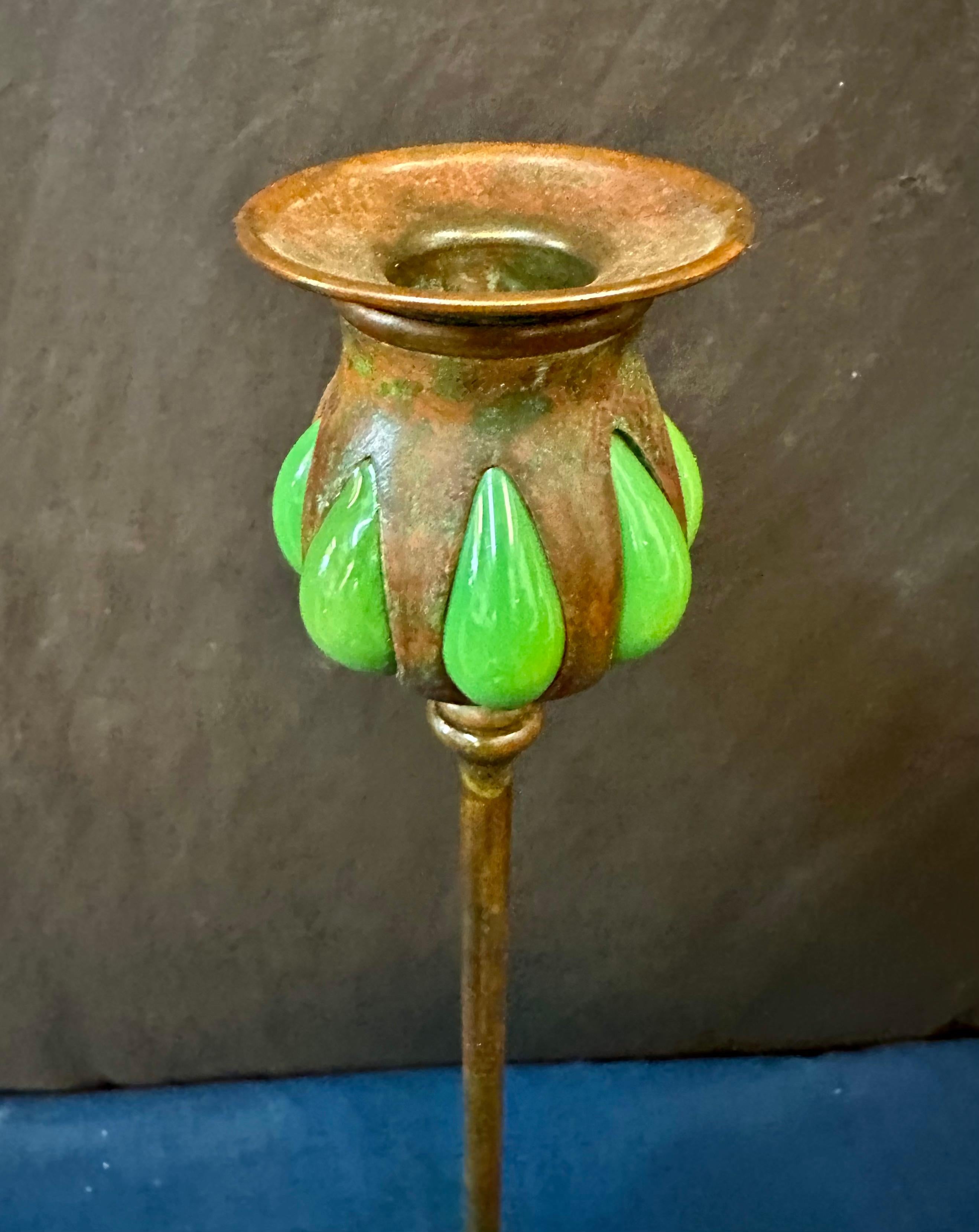 This vintage early 20th century authentic Tiffany Studios candlestick is decorated with blown out green color favrile art glass in its candle cup. The candlestick has beautiful dark brown patination complimenting its overall appearance. The base is