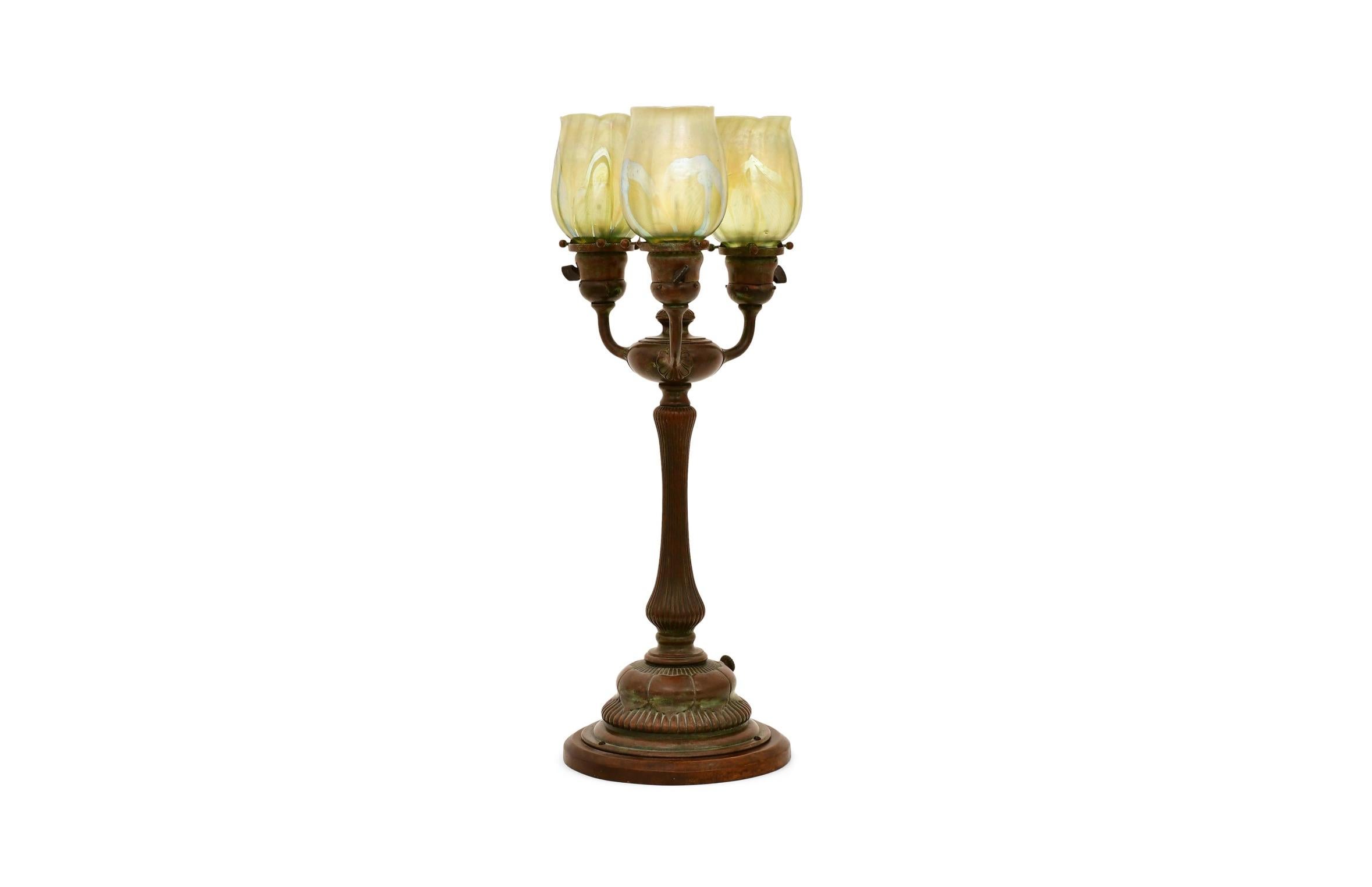 Eine exquisite und hochgradig sammelwürdige dreiflammige Newel Post Tischlampe von Tiffany Studios, New York, um 1910 hergestellt. Dieses elegante Stück aus dem frühen 20. Jahrhundert ist ein Beispiel für Tiffanys meisterhaftes Gleichgewicht aus