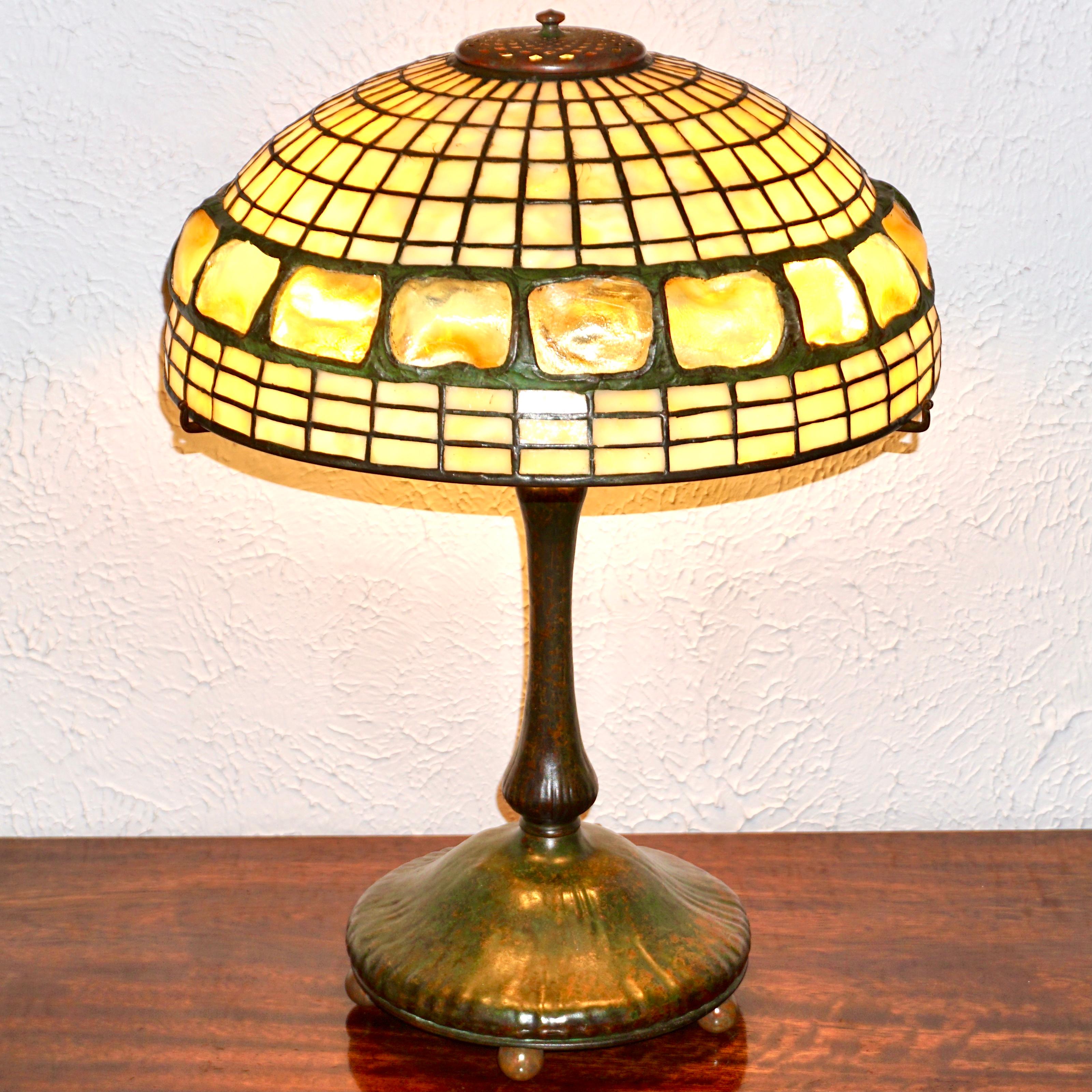 Tiffany Studios Art Nouveau Table lamp having turtle back and geometric shade with brown and green patinated bronze mushroom base. Turtle back glass chunks are iridescent and cased set in a leaded band with geometric square dichromatic glass design