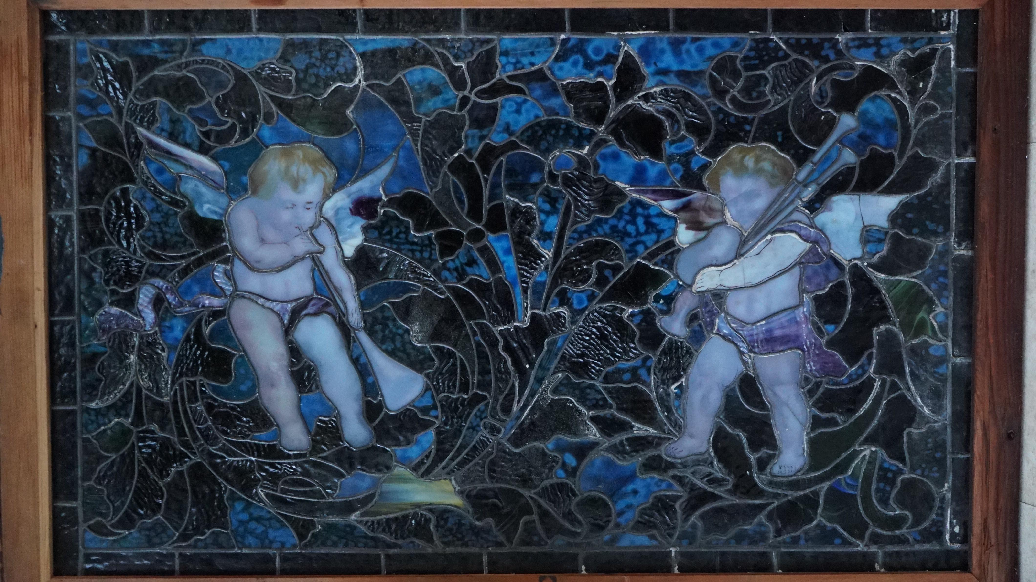 A beautiful example of a leaded art glass music window depicting wing cherubs, playing musical instruments, executed with Tiffany furnace mottel lamp glass set as the background

We acquired this window because we were told it was from the Frederick
