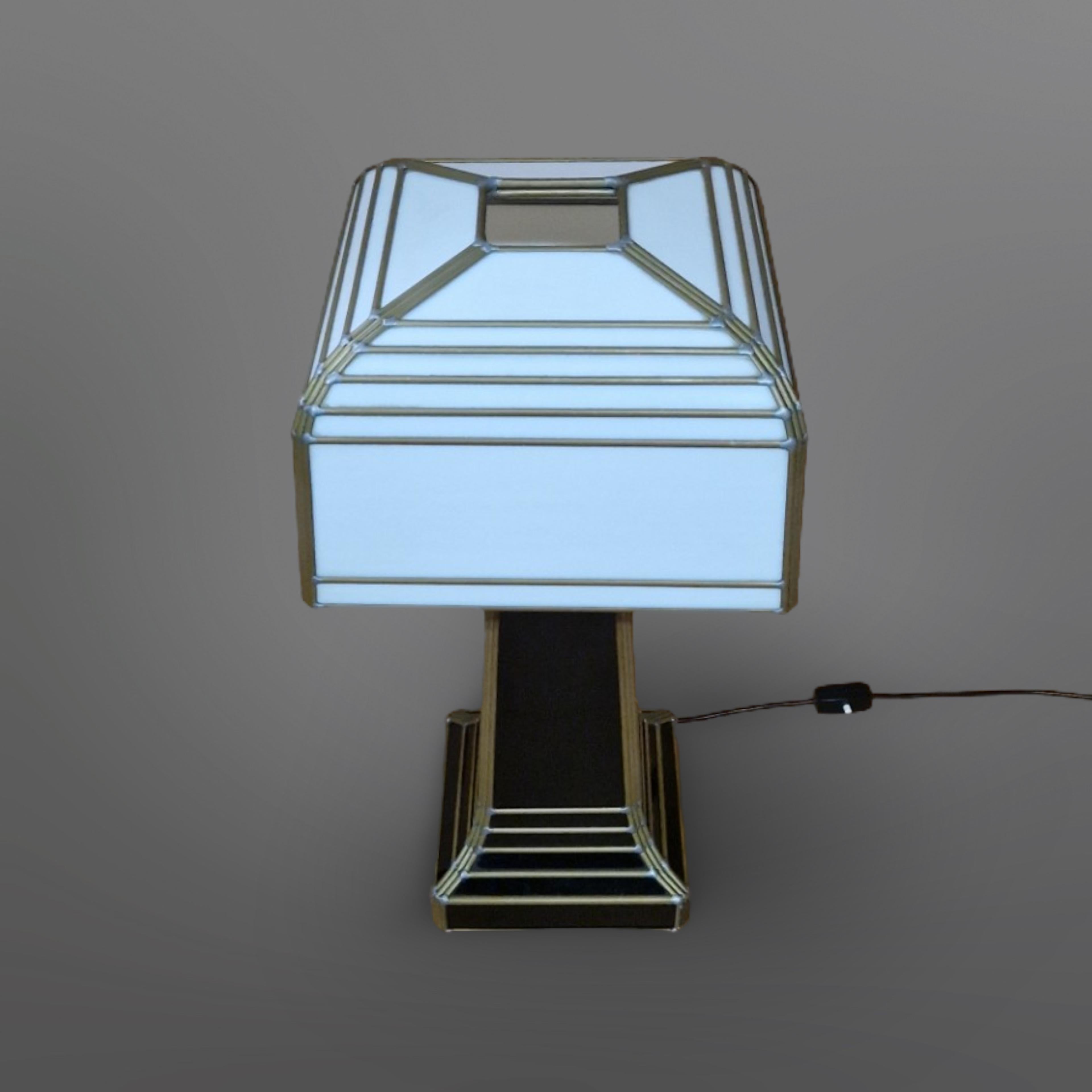 This impressive handmade table lamp is made from stained glass. The glass is set in brass strips and hand soldered. It was made in the 1960s in Germany. The shade is removable and is made from opaque white glass. The base is made from black glass.