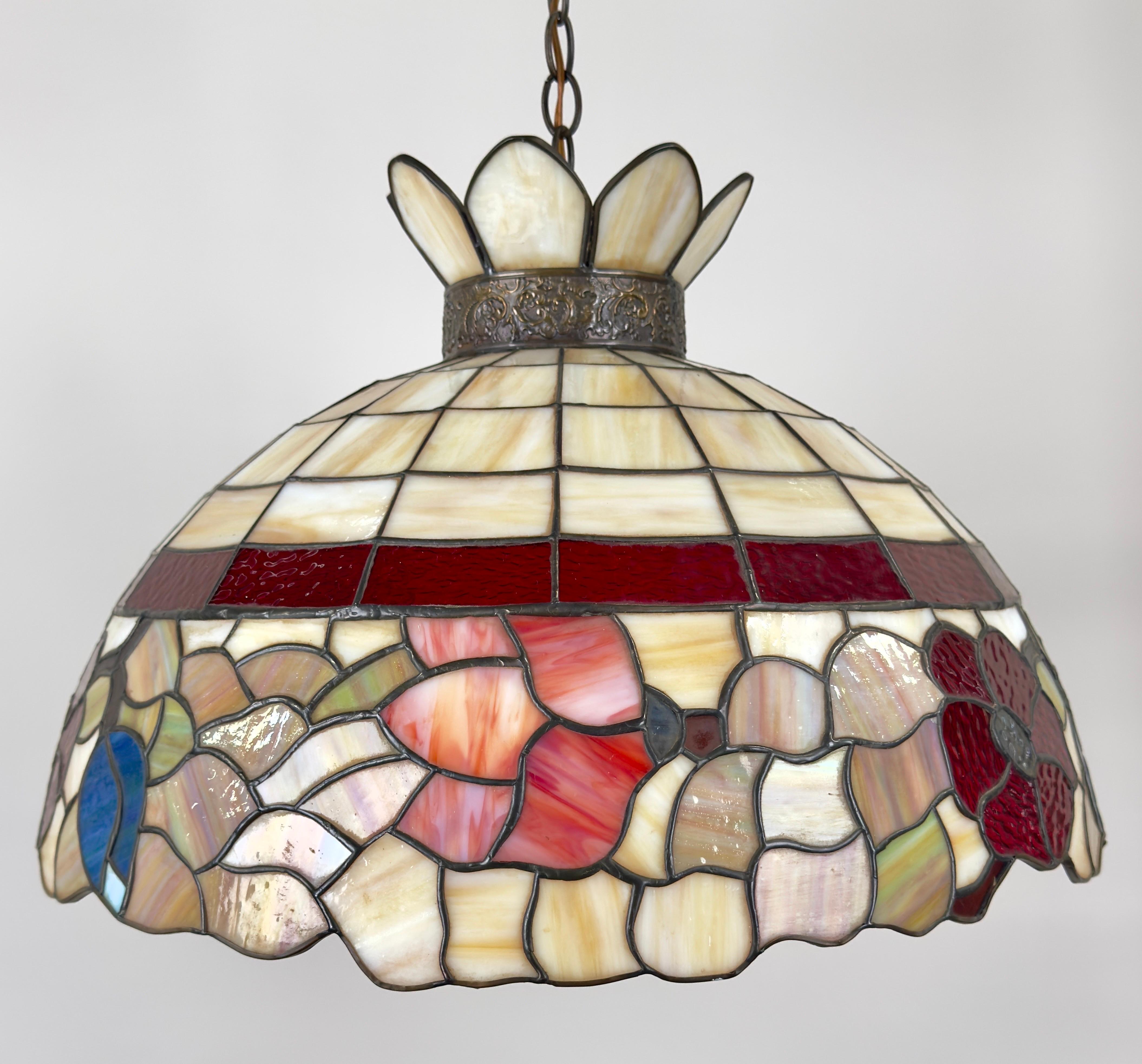 Una hermosa lámpara colgante de vidrieras Art Nouveau de estilo Tiffany con un diseño en forma de cúpula, que muestra una rica gama de colores e intrincados dibujos. La parte superior está formada por paneles rectangulares en tonos suaves y cálidos,