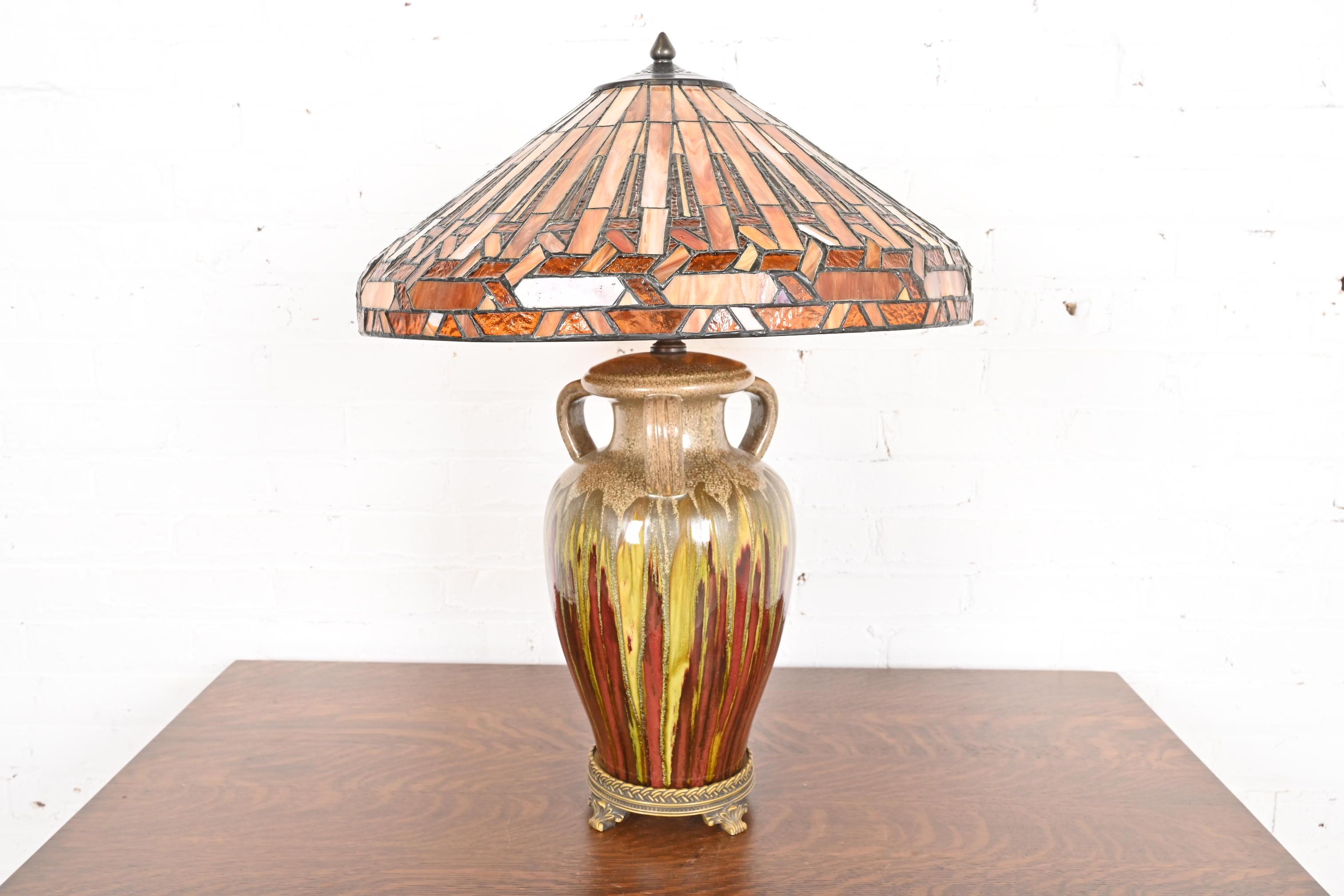 Una splendida lampada da tavolo in stile Arts & Crafts

Circa alla fine del XX secolo

Base in ceramica smaltata a forma di urna, con paralume in vetro colorato. 

Misure: 20,25