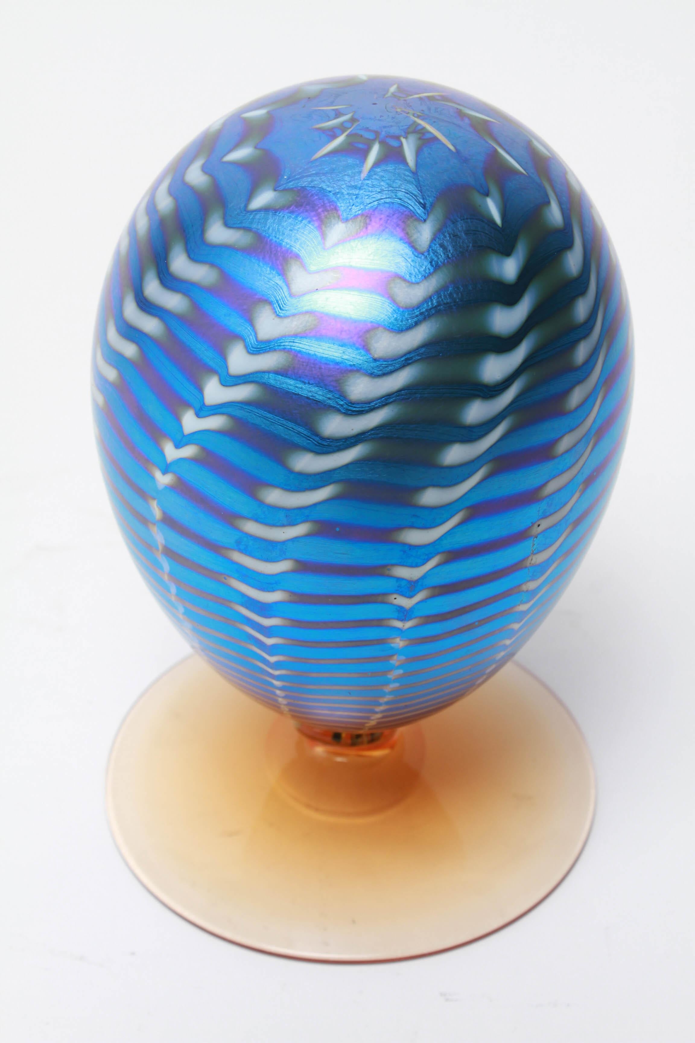 Tiffany style iridescent pulled-feather art glass egg on an orange glass base. The piece is in great vintage condition with age-appropriate wear.