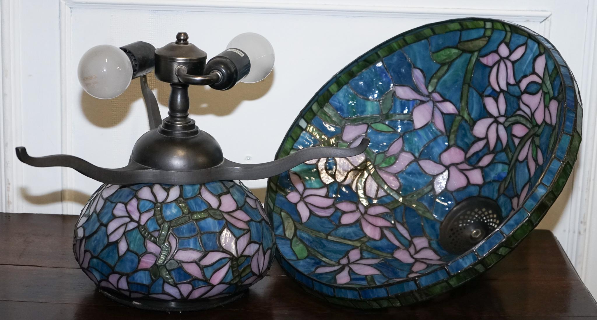 
Antigüedades de Londres



Esta exquisita pieza, una llamativa lámpara de sobremesa de estilo Tiffany inspirada en la época del Art Nouveau, presenta una pantalla de cristal de colores hecha a mano y una base iluminada a juego, con un motivo de