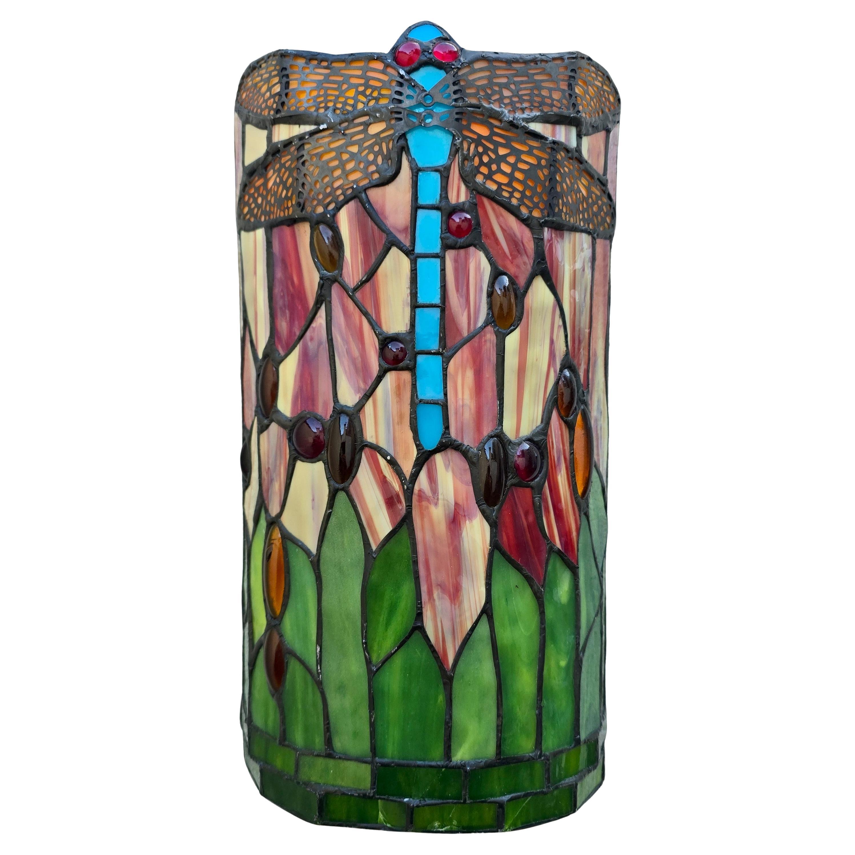 Aplique decorativo de vidrieras con un atrevido motivo de libélula en el clásico estilo Tiffany. Hecha a mano con cristal opalescente, cabujones joya y soldadura de lámina de cobre. Una vibrante luz de acento Art Nouveau Revival.

Este expresivo