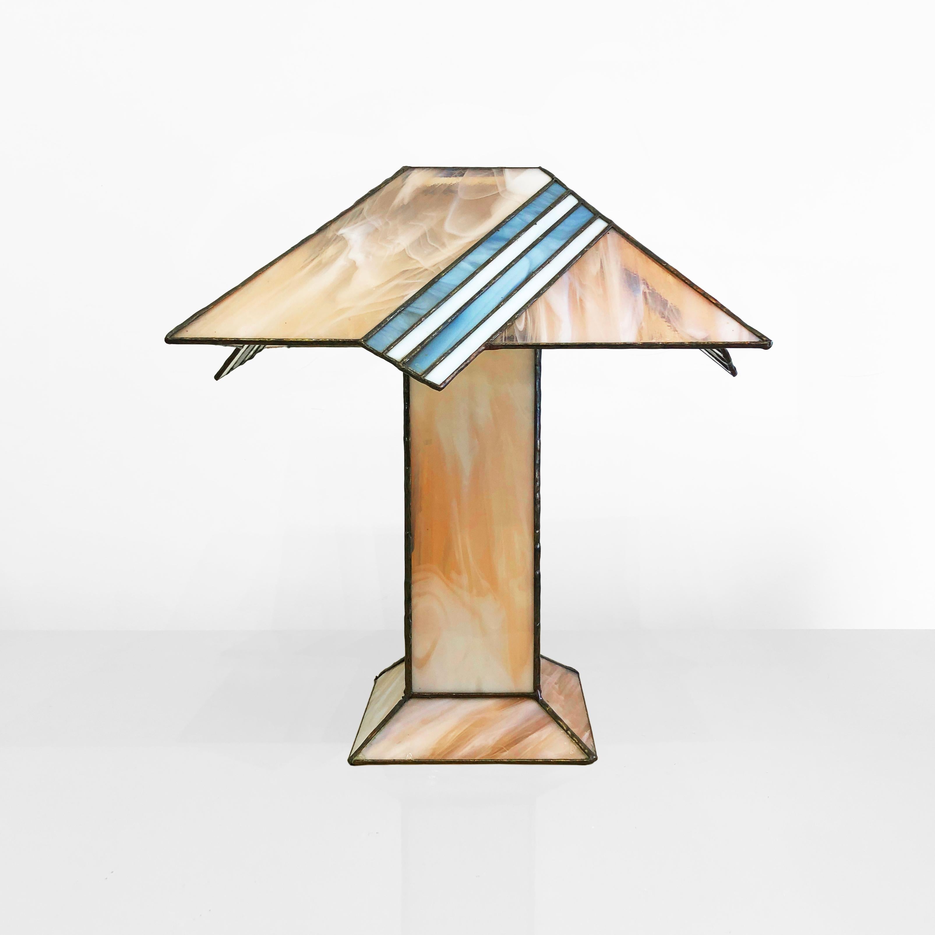 1980s stylish and elegant high quality table lamp in Tiffany Art Deco style. The shade and body are made of pinky salmon pastels and cream-coloured stained glass which features a diagonal stripped baby blue pattern on the shade. The stained glass