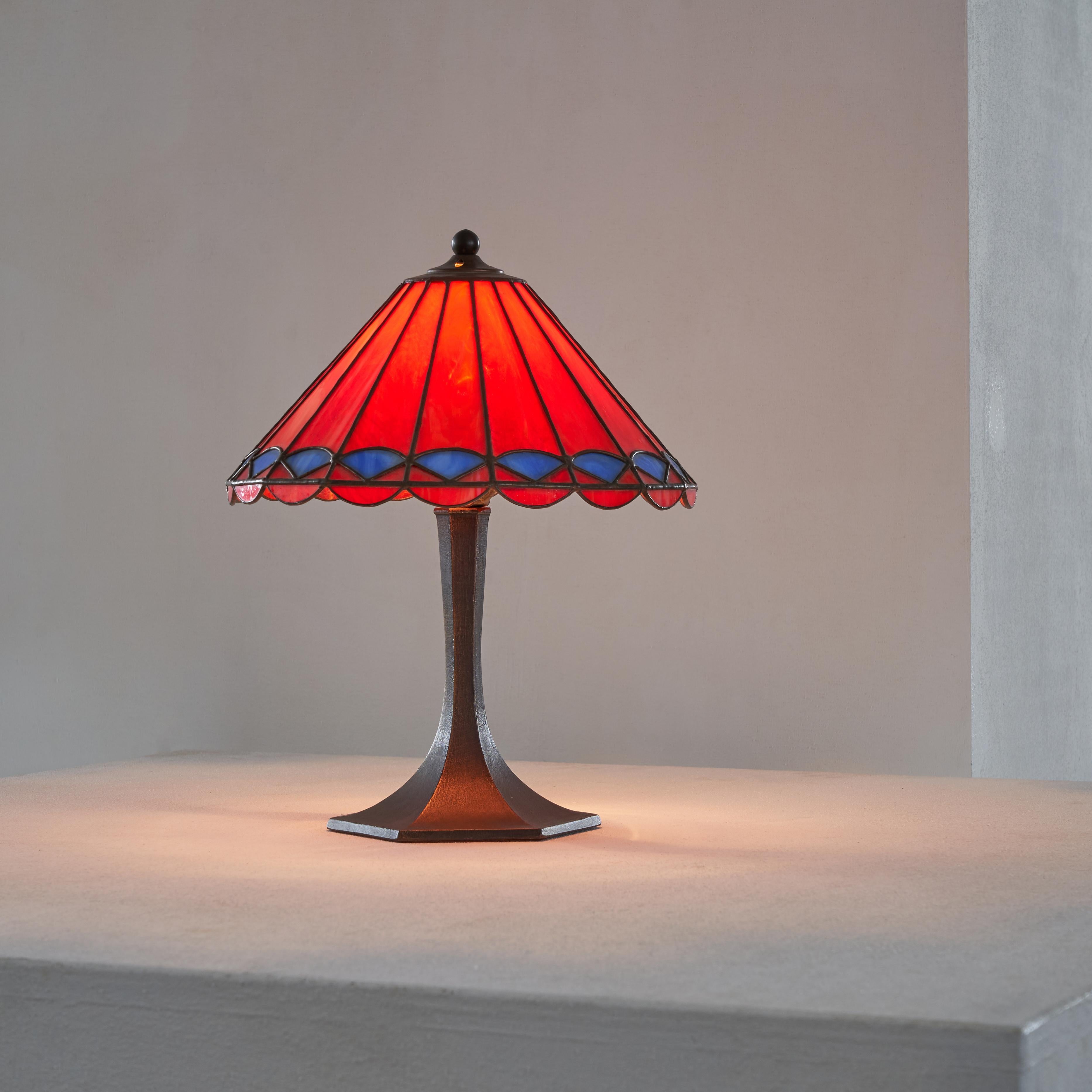 Tiffany Style Table Lamp in Metal and Stained Glass 1950s.

Wonderful and colorful table lamp in Tiffany style. Stained glass in red and blue, with a sculptural base. This table lamp is a beautiful piece of vintage lighting, crafted in the 1950s,