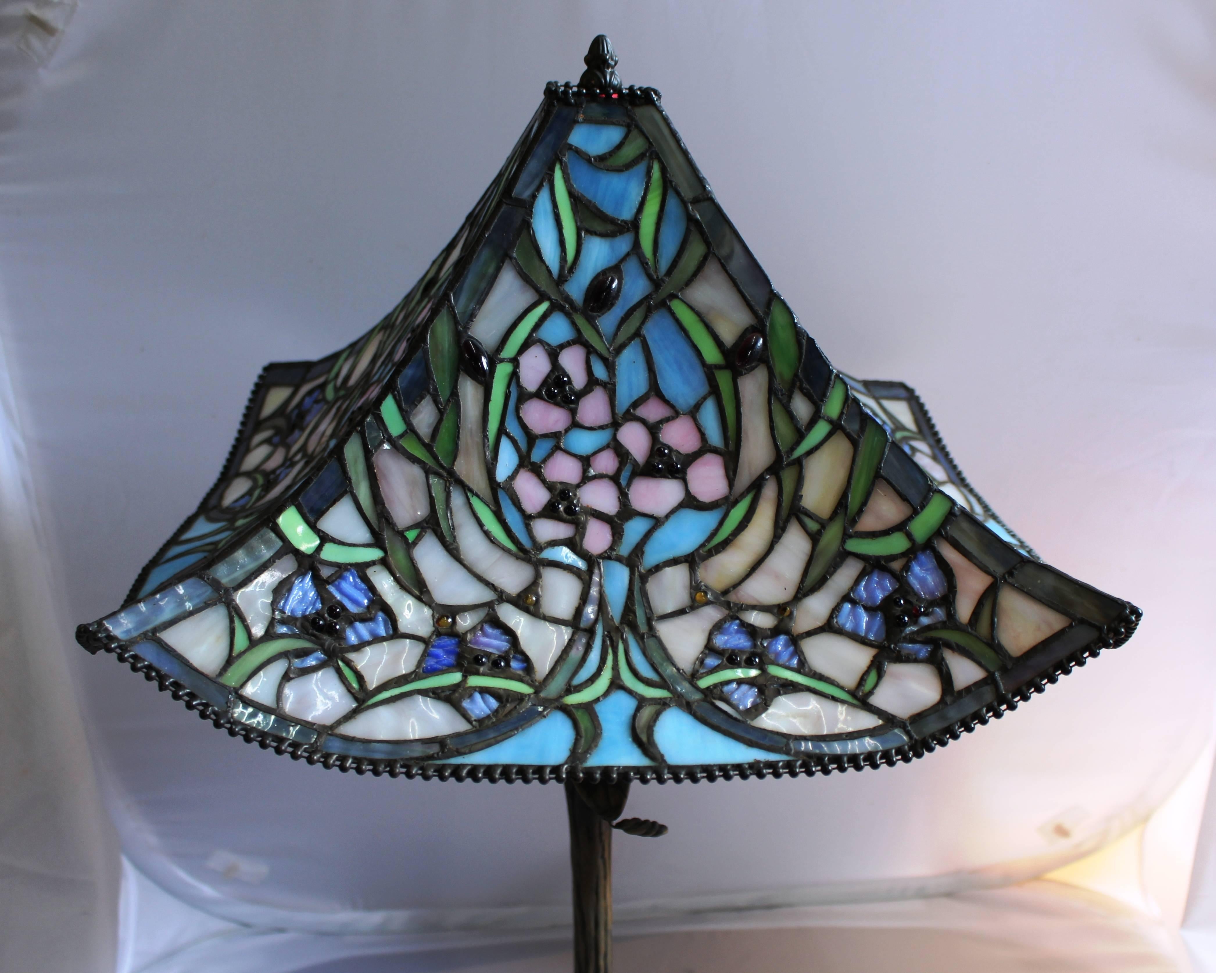 Measures: Shade width 51 cm 20 in
Height 67 cm 26 1/2 in.




Decoration Tiffany style, genuine glass with beautiful colors forming floral design. Flowers are pink with green leaves. Lampshade is decorated with purple, amber and black beads.