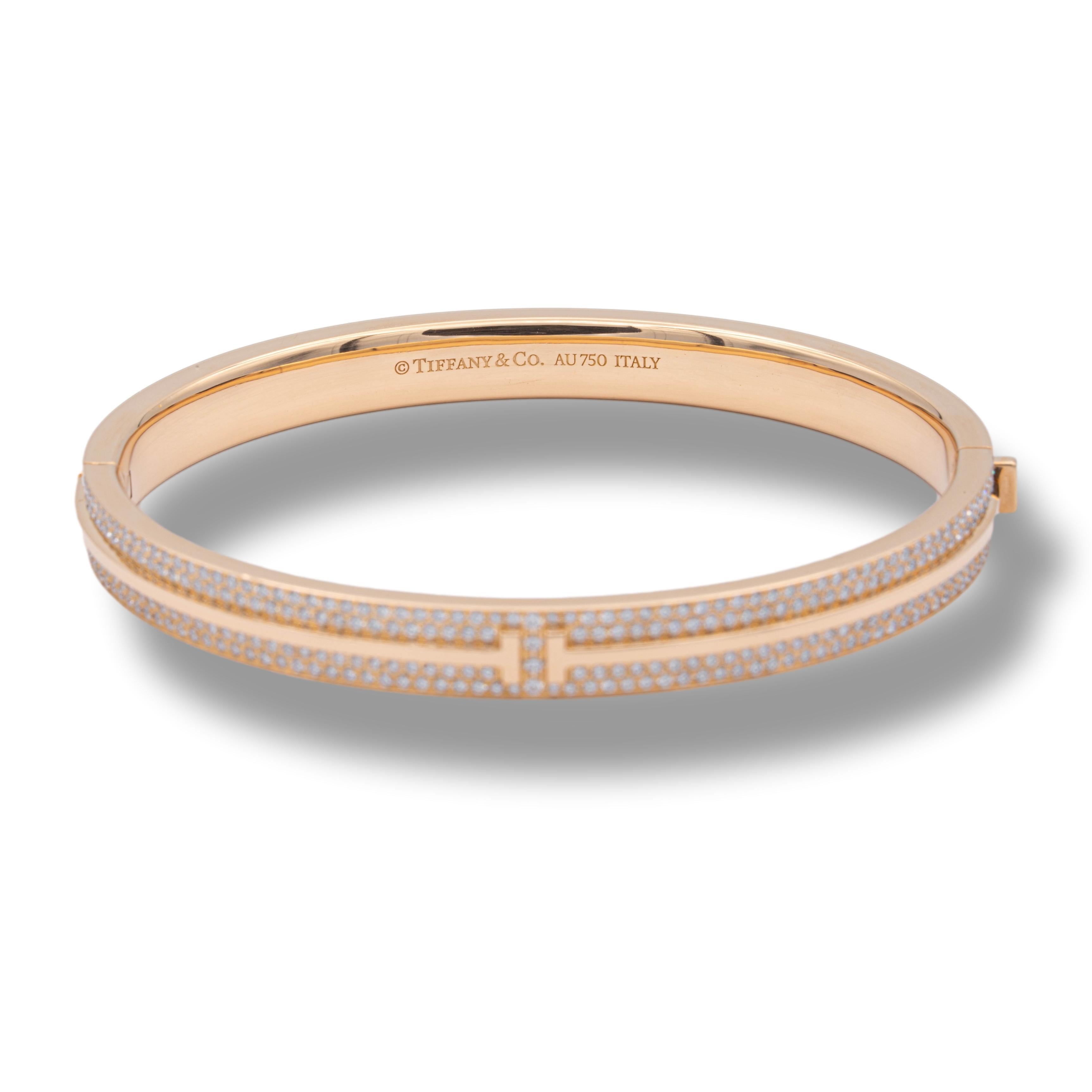 Tiffany & Co. T motif pave diamond bangle bracelet finely crafted in 18 karat rose gold with a double safety hinge closure.
The bracelet has pave set diamonds halfway across the top weighing a total of 0.82 cts. Medium size, which fits wrists up to