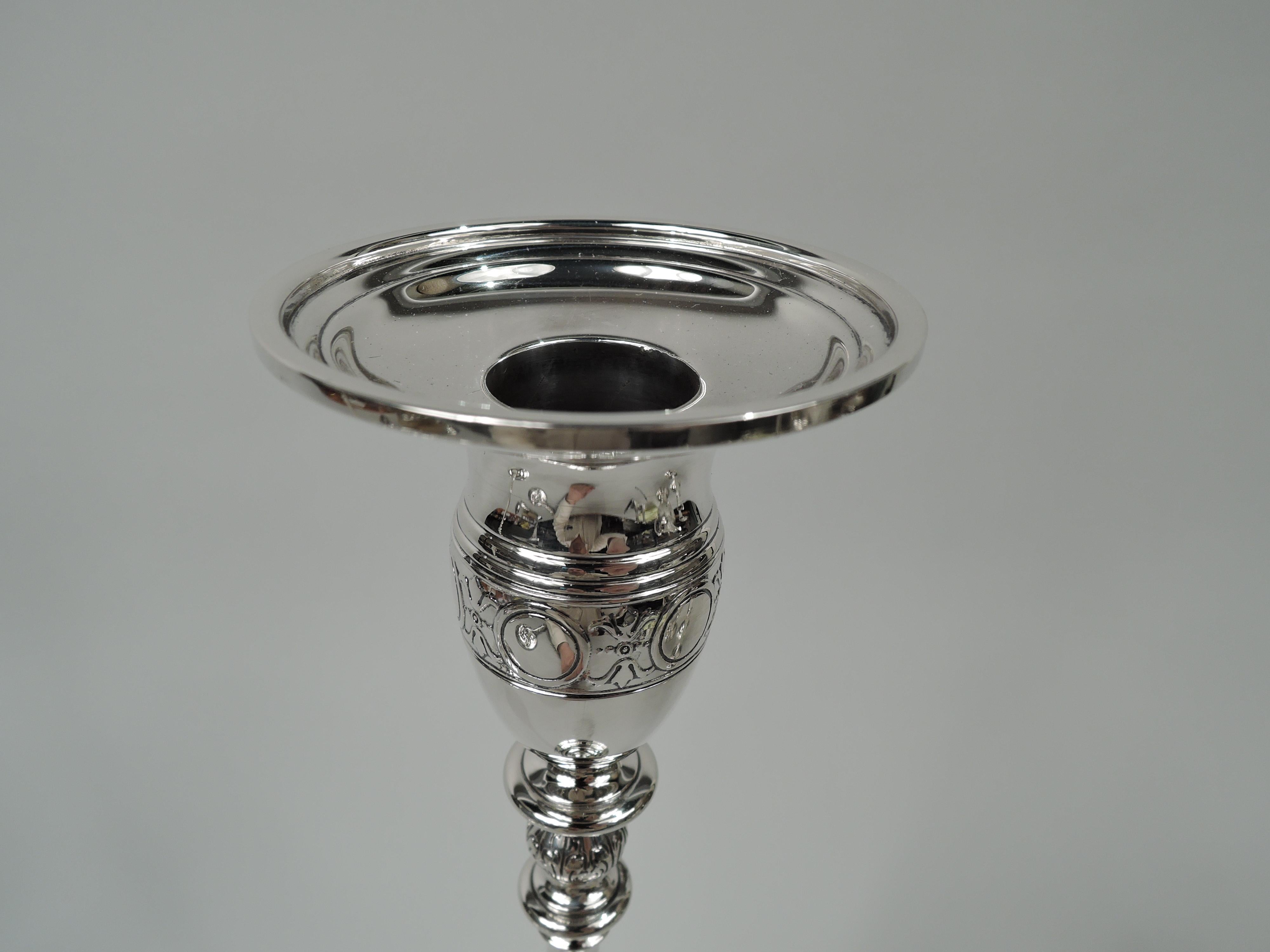 Art Deco sterling silver candlesticks. Made by Tiffany & Co. in New York, ca 1925. Ovoid socket with detachable bobeche on elongated and knopped baluster shaft; raised foot on round base. Engraved and acid-etched Modern Classical ornament including