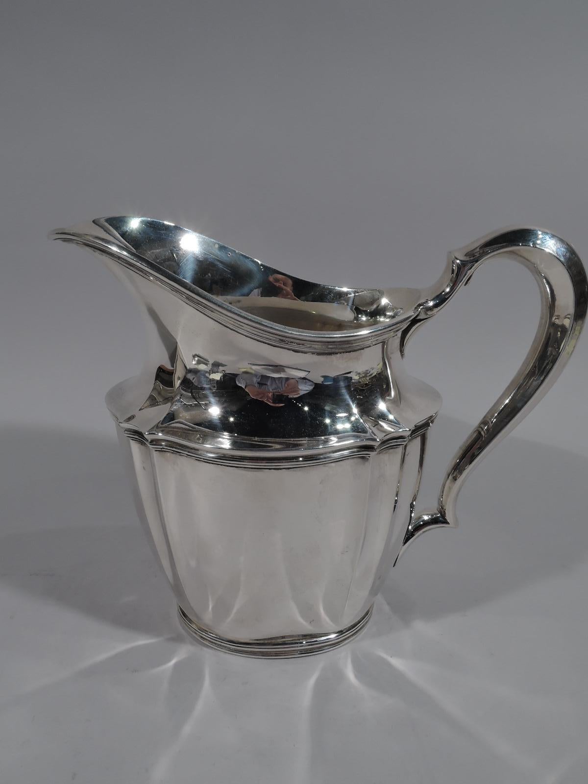 Traditional sterling silver water pitcher. Made by Tiffany & Co. in New York, circa 1910. Tapering oval body, helmet mouth, and high-looping handle. Restrained fluting and reeding. Fully marked including pattern no. 14997D and director’s letter m.