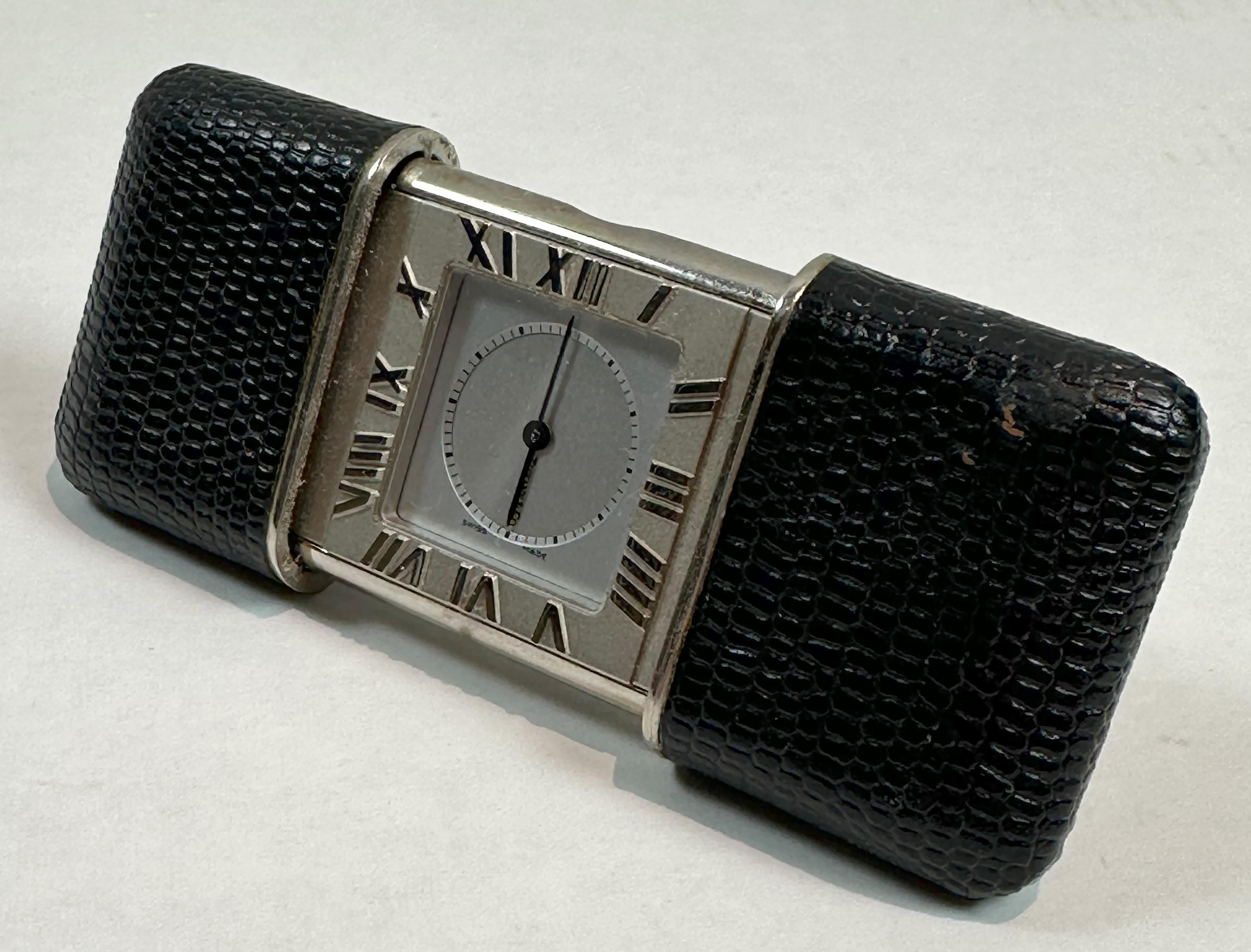 Une belle pièce de Tiffany & Co. Horloge de voyage atlas de fabrication suisse. L'intérieur est plaqué argent et l'extérieur est recouvert de cuir d'alligator noir.  Se referme par glissement pour protéger l'horloge lors des déplacements.

En très
