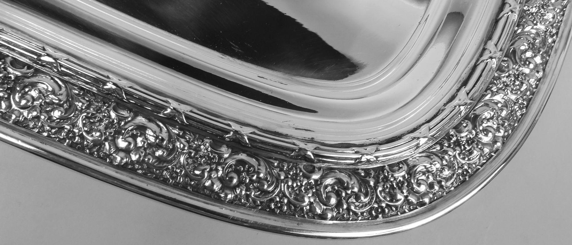 Bandeja de té clásica victoriana de plata de ley. Fabricado por Tiffany & Co. en Nueva York, hacia 1880. Rectangular con esquinas curvadas. Sobre el hombro, una densa cenefa de roleos y flores en bajorrelieve, que continúa su profusión hasta las