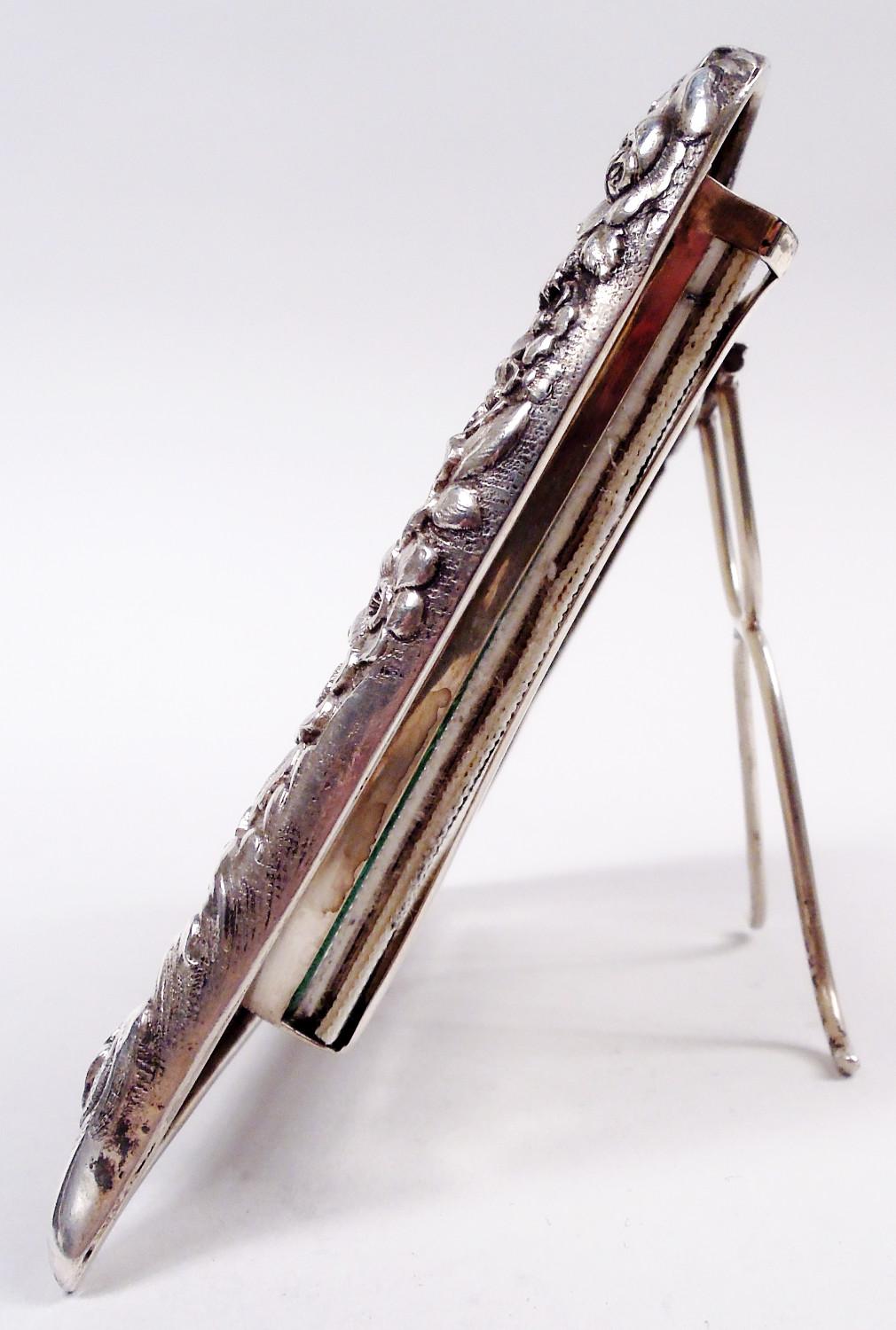 Marco clásico victoriano de plata de ley. Fabricado por Tiffany & Co. en Nueva York, hacia 1886. Ventana rectangular en el mismo marco con un denso repujado de hojas y flores; parte superior elevada con remate de hojas y pies separados. Con cristal,