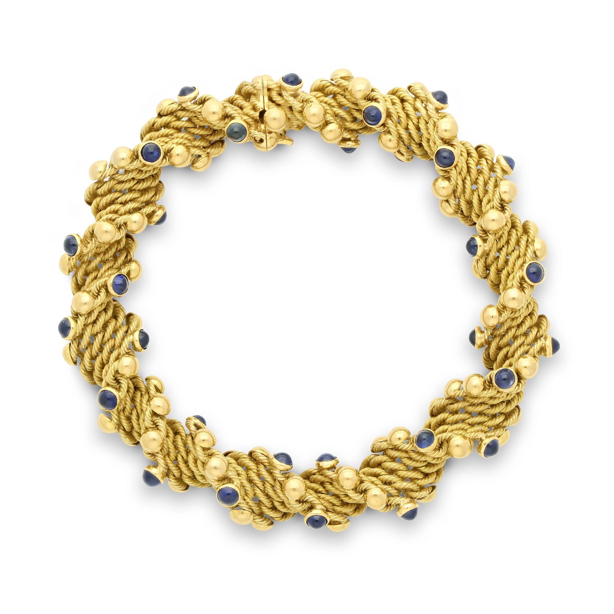 A vintage 18ct yellow gold and sapphire bracelet by Tiffany & Co. circa 1970, workmaster Georges Lenfant. The bracelet is designed as a helix of textured yellow gold embellished with gold spheres alternating with bezel set cabochon sapphires.