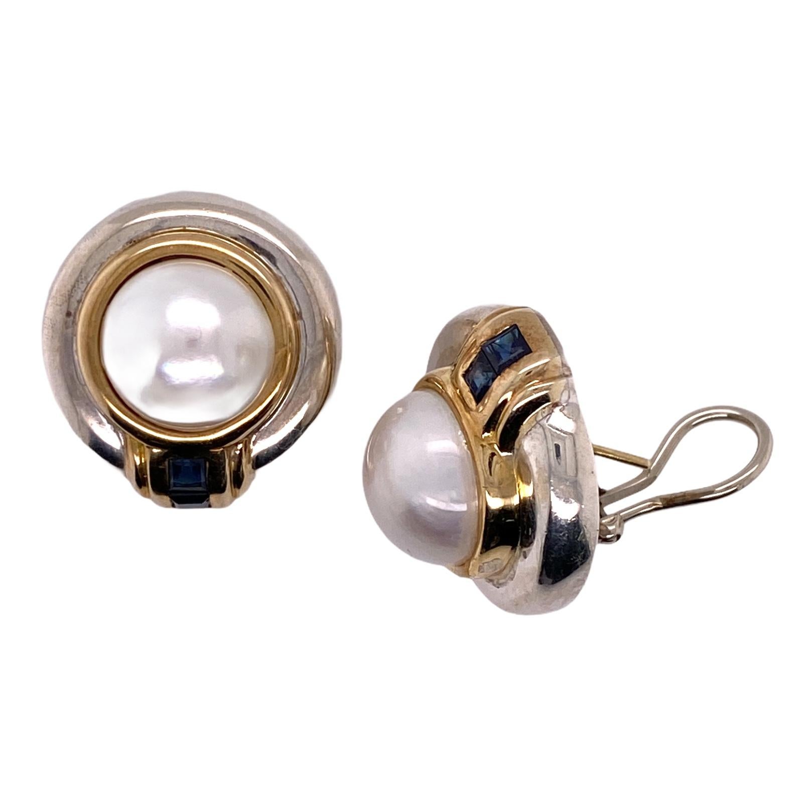 Rare vintage Tiffany & Co. earrings fashioned in 14 karat yellow gold and sterling silver. The earrings feature 12.5mm mabe cultured pearls and 4 princess cut sapphire gemstones. The round earrings measure 22.5mm in diameter, crafted with lever