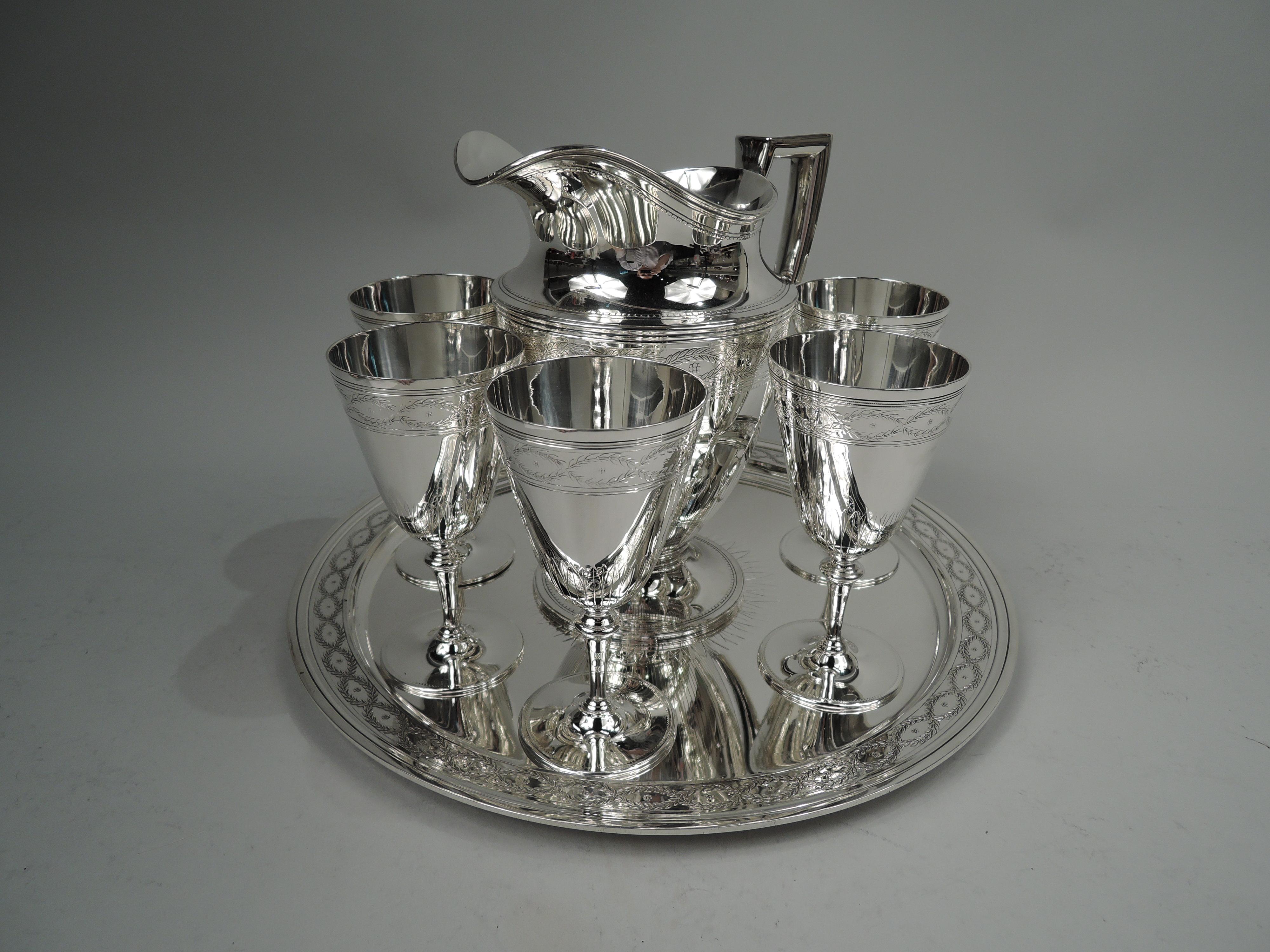 Winthrop sterling silver drinks set. Made by Tiffany & Co. in New York, ca 1925. This set comprises pitcher, 6 goblets and tray. The pitcher has curved and tapering bowl, raised foot, scrolled-bracket handle, and helmet mouth. The goblets have