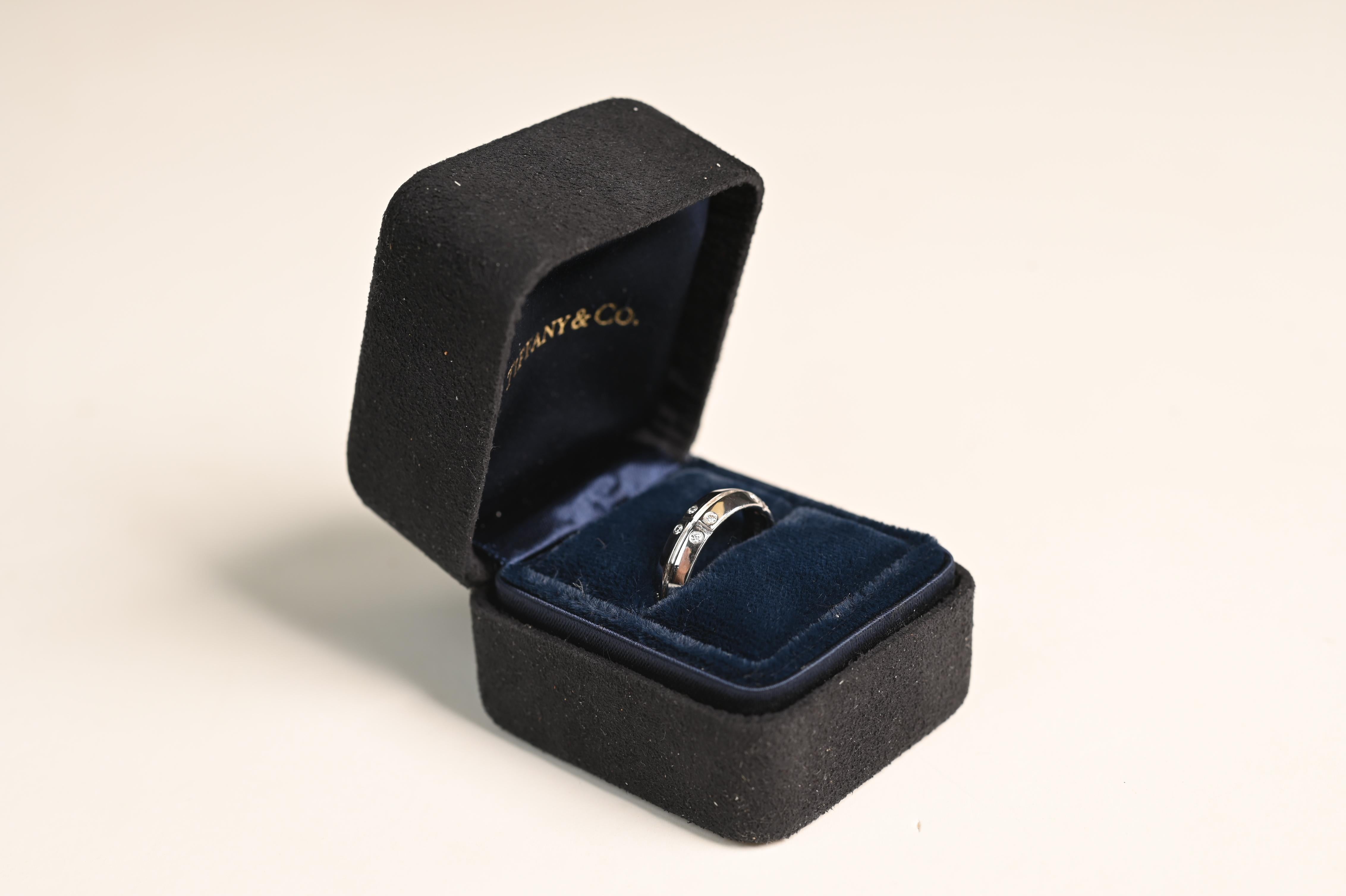 Esta exquisita alianza de oro blanco de 18 quilates y diamantes es una pieza magistralmente elaborada a mano por Tiffany & Co. Diseñada con elegancia y precisión, la banda presenta un distintivo surco horizontal que la rodea en su totalidad,