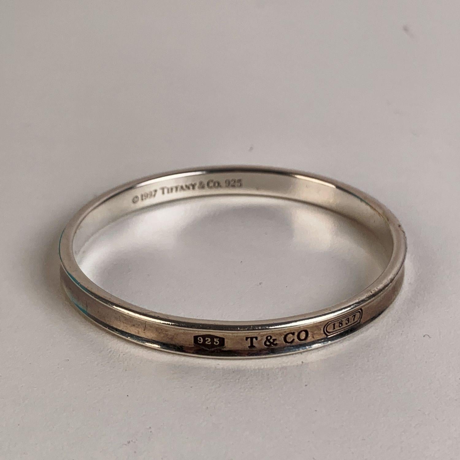 Beautiful sterling silver bangle bracelet by Tifffany& Co. The bracelet has a concave design and is engraved with the year 1837, the year Tiffany was founded. '925' hallmark engraved on top. Copyright symbol with '1997 Tiffany & Co.' engraved