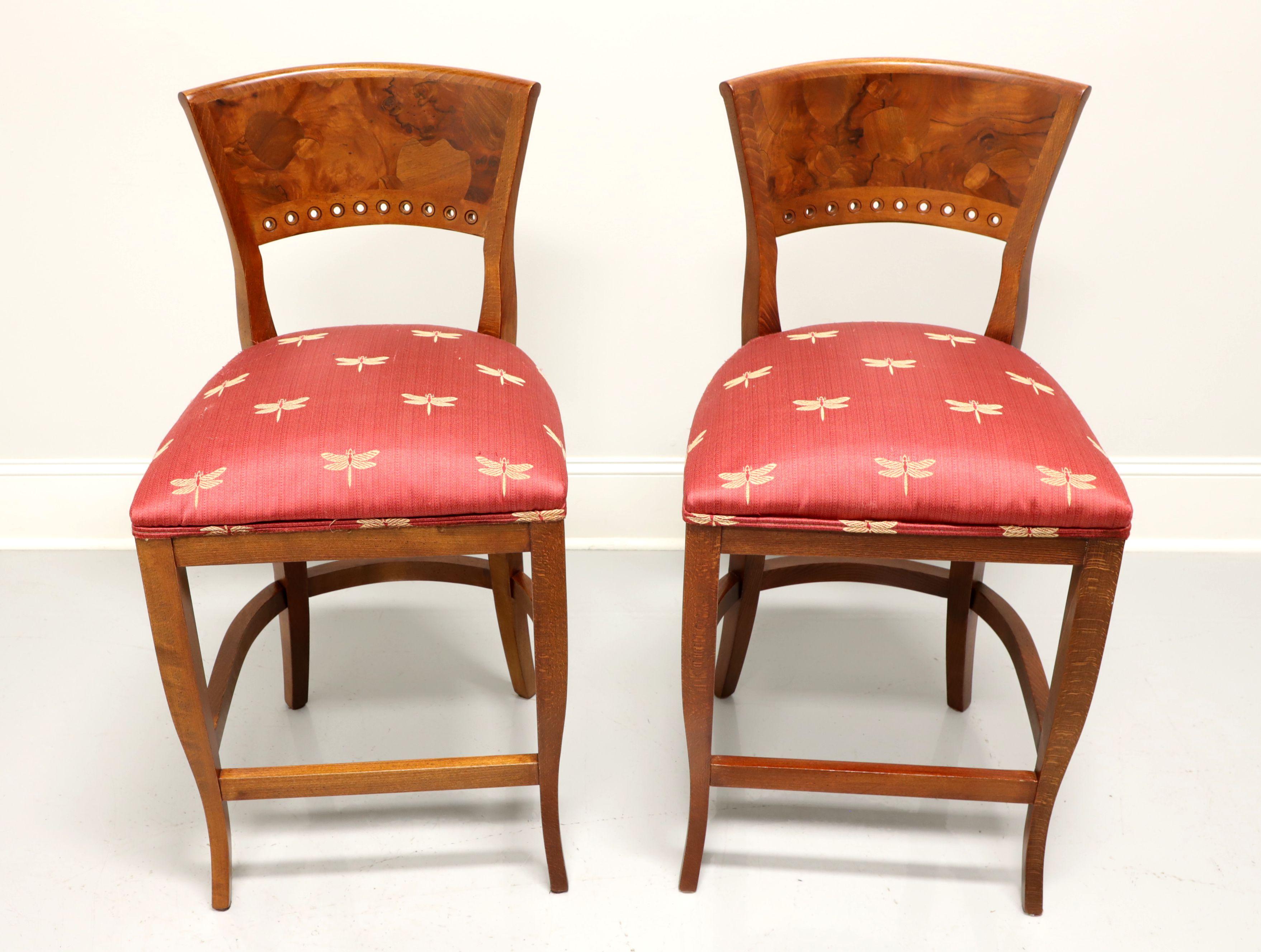 A pair of Neoclassical style counter height stools by Emerson et Cie, of High Point, North Carolina, USA. Tiger & burl oak backrests, salmon colored fabric with gold fireflys upholstered seats, saber legs with curved stretchers and footrest. Made in