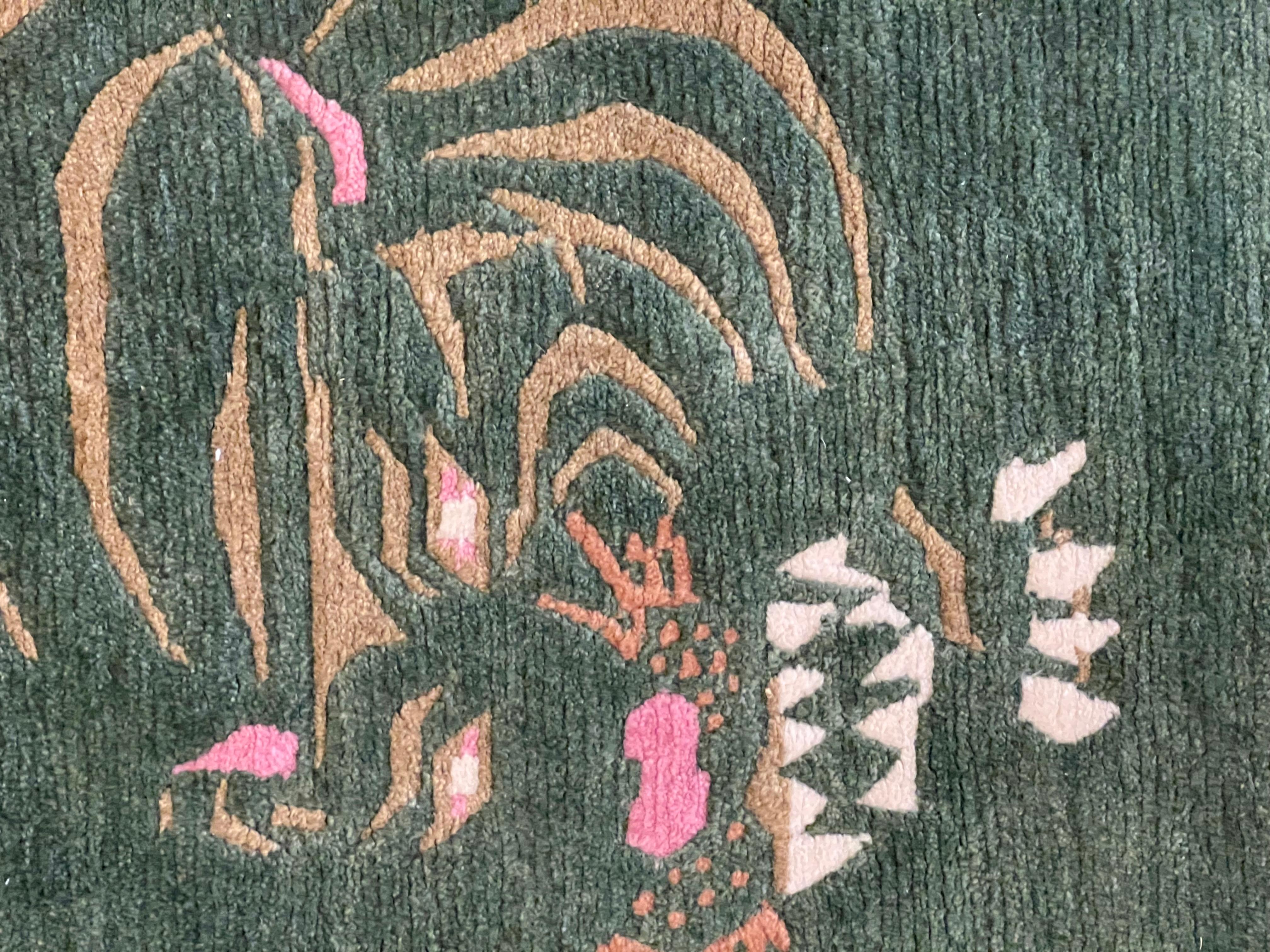 Carpet of Nepalese production, knotted with hand spun wool with Tibetan knot. The background is grass green and the tiger, represented with evil eyes and powerful teeth as she is about to pounce on her prey, is a symbol of strength and