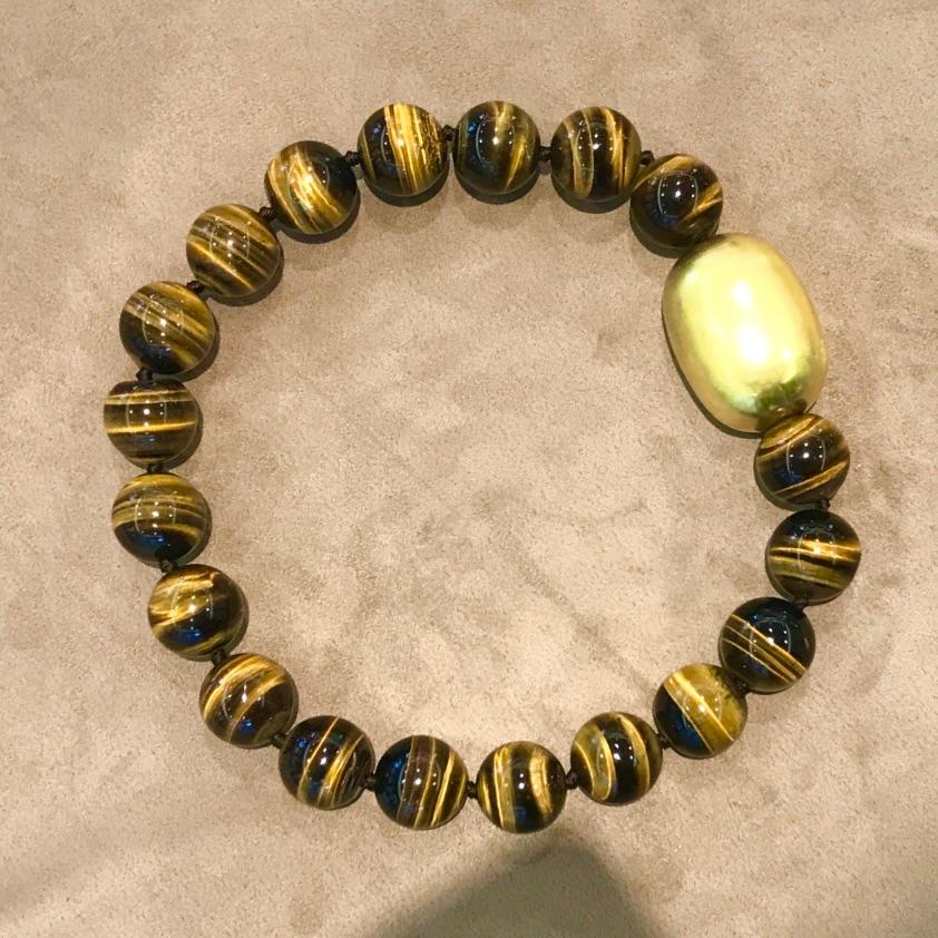Un ensemble de grandes perles d'œil de tigre, nouées individuellement à un grand fermoir en forme de dôme, plaqué or sur une base polie 