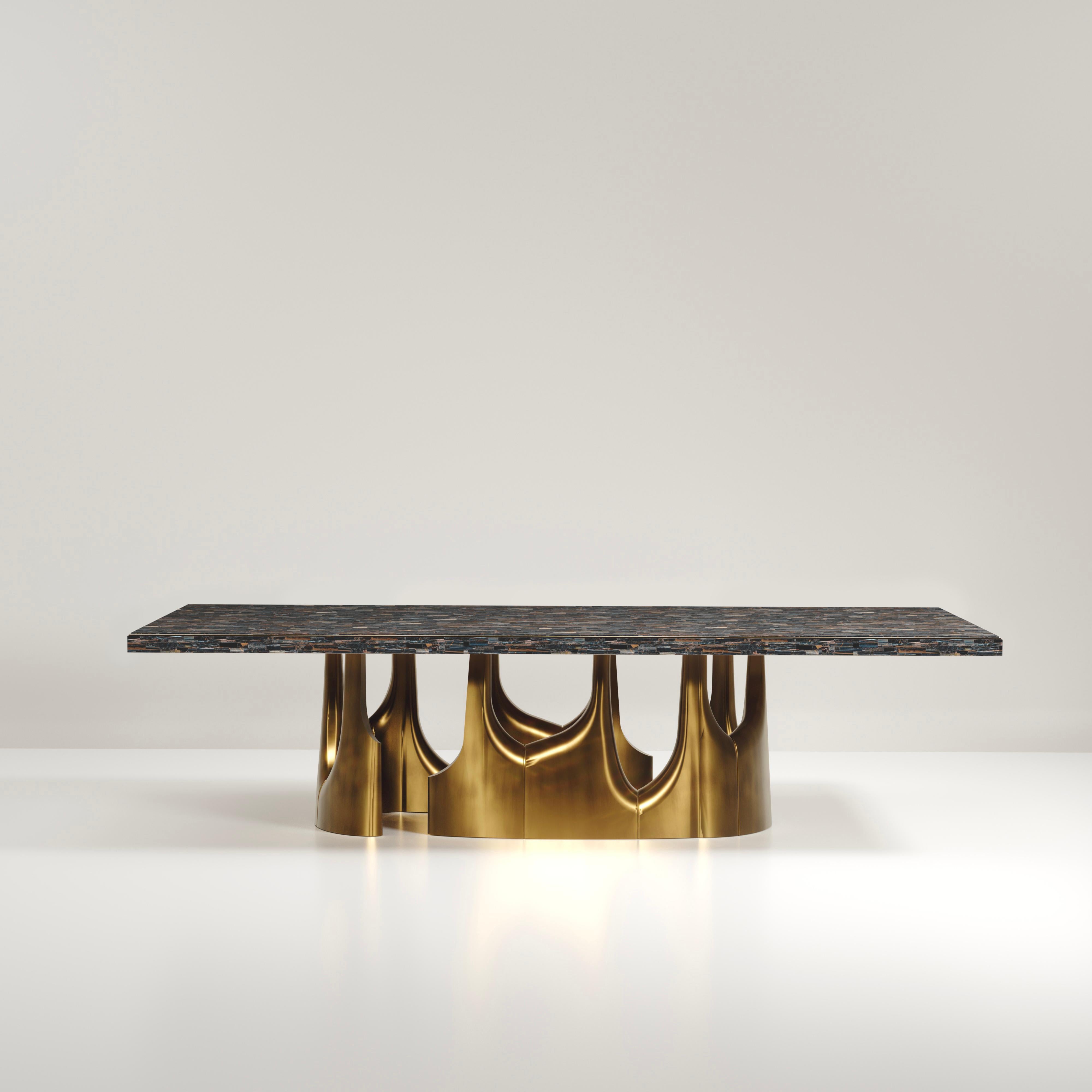 The Triptych II dining table by R&Y Augousti is a stunning multi-faceted sculptural piece. The beautiful hand craved details on the long clustered bronze-patina base demonstrate the incredible artisan work of Augousti. The top is in an incredible