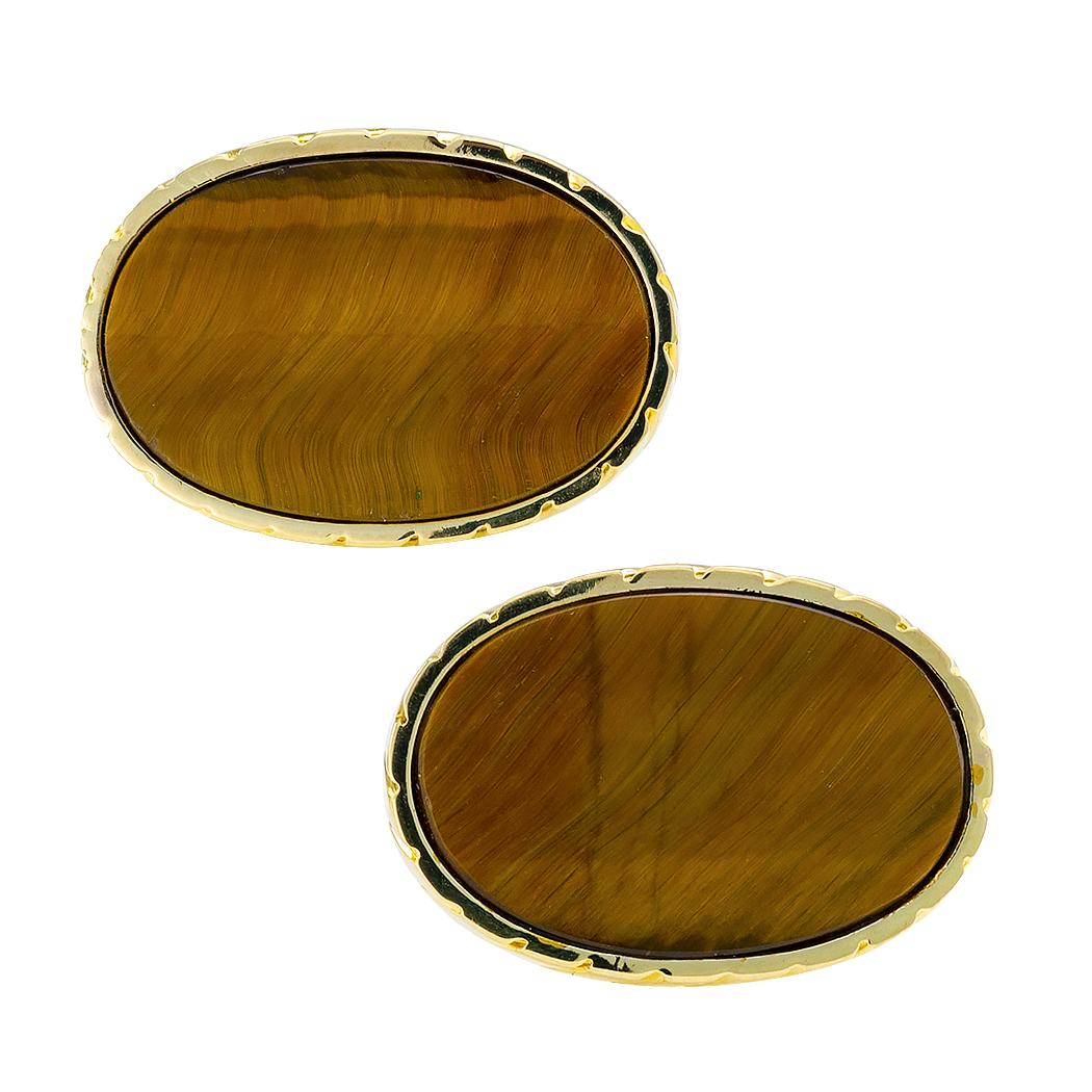 Tiger eye and gold cufflinks circa 1970. Featuring a pair of very distinctive, flat buff-top, oval tiger eye, set into conforming fluted bezels, to the back connectors inlaid with tiger eye, mounted in 14-karat yellow gold. We love the larger size