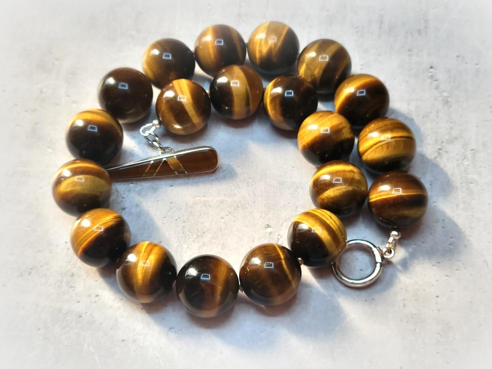 The length of the necklace is 18 inches (45.7 cm). The size of the very high-quality round beads is 20 mm.
The tones of the beads are a wondrous golden brown, caramel gold, and silky — gorgeous warm shades.
The tiger eye was named for the