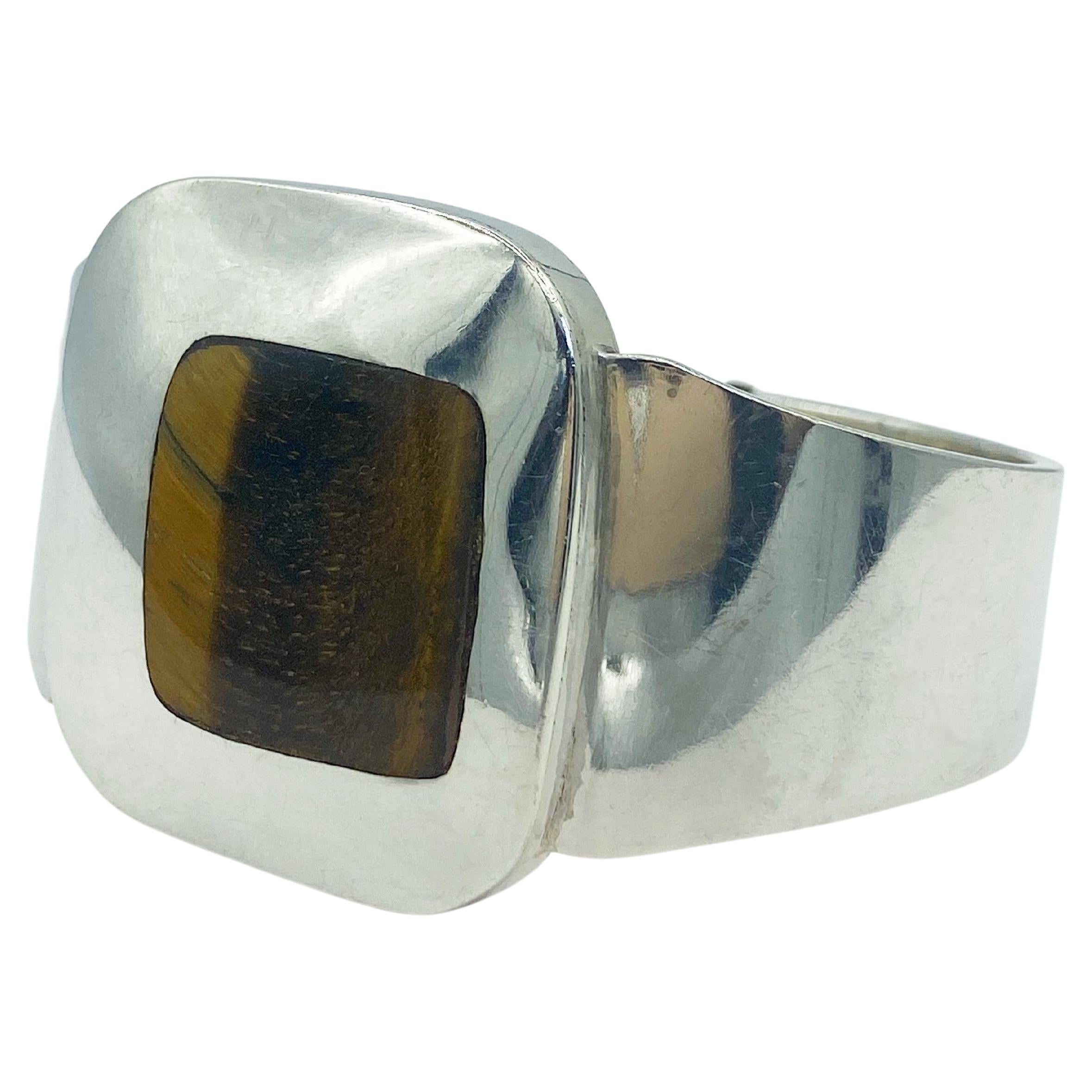 Funky, edgy, vintage Tiger's Eye and Sterling Silver clamper bracelet circa the 1960s. It has a Pop Art feel, with the Tiger's Eye stone set off-center within the domed-square face. The bracelet opens simply with a spring hinge.

Hallmarked with the