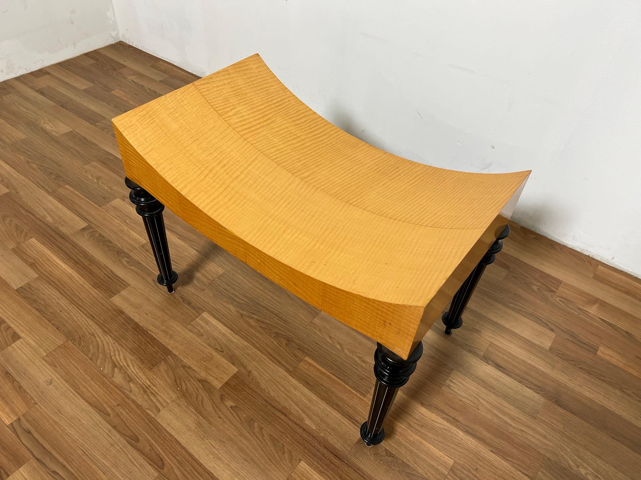 A studio crafted post modern bench with quilted tiger maple seat and contrasting black lacquered turned legs delivers a contemporary interpretation of the Biedermeier style.