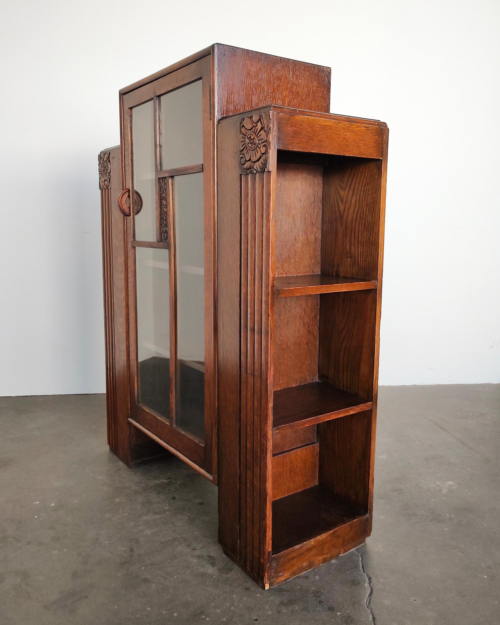 Tiger oak Art Deco cabinet with glass doors and side shelves. Beautiful design with hand carved details. Perfect as a bar or display cabinet or bookshelf. Overall great vintage condition. 

32.75