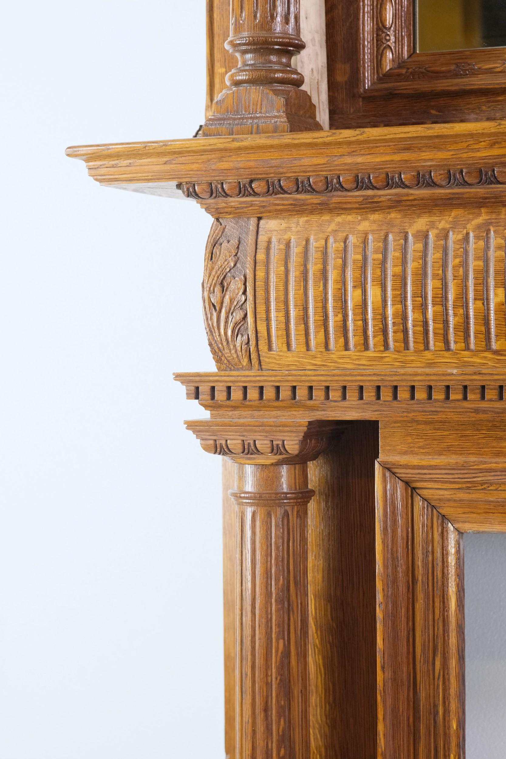 Turn of the century two tier or double decker tiger oak mantel with fluted columns and mirror. It is accented with carved foliage details, egg & dart design and dentil molding. There are two sets of fluted columns, one set on the bottom half and one