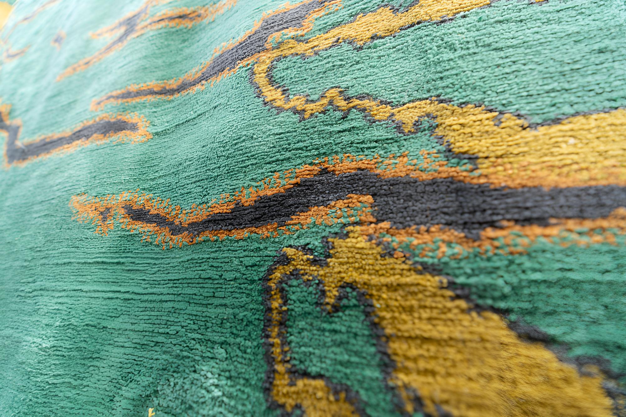 Dieser beeindruckende handgefertigte Teppich aus Nepal ist eine faszinierende Mischung aus traditioneller Handwerkskunst und zeitgenössischem Design. Es ist aus hochwertiger Wolle gewebt und zeigt einen leuchtend grünen Hintergrund, der mit