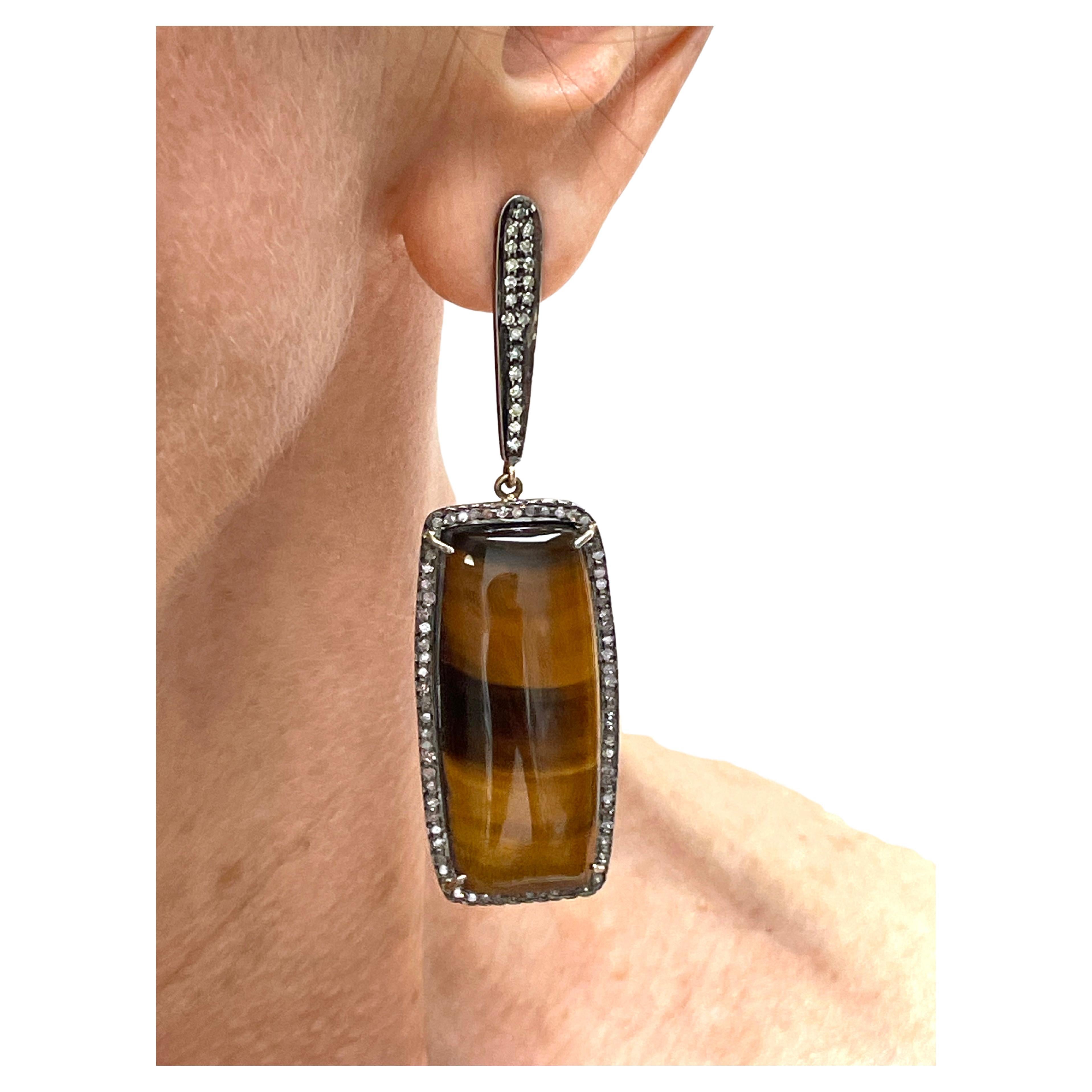 Description
Lustrous, large and mesmerizing beautifully matched pair of cognac and rich brown iridescent Tiger’s Eye cabochons, surrounded with champagne diamonds, dangle from a pave diamond post. The combination of soft color diamonds paired with