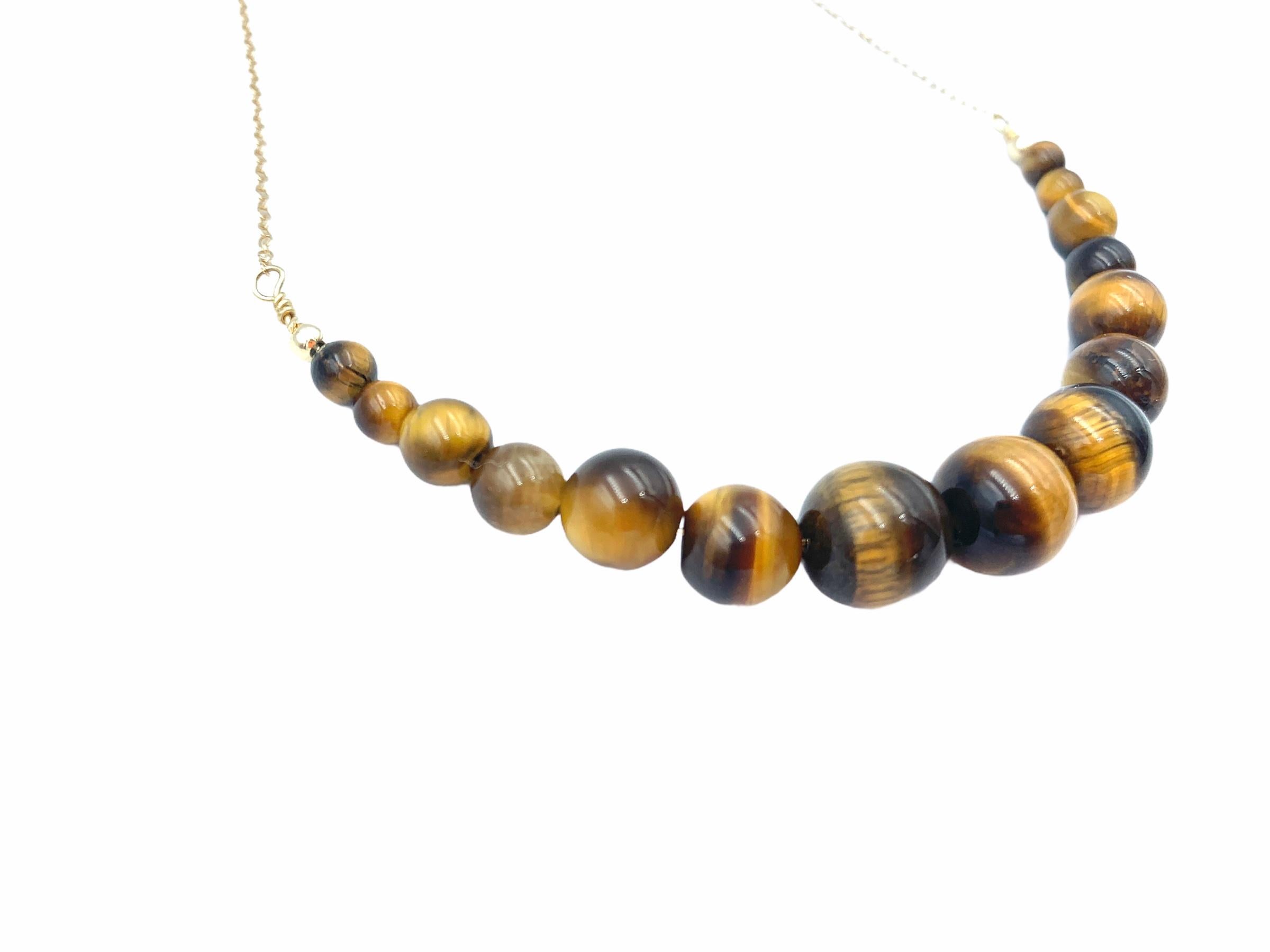 Hand made using 14 carat Yellow Gold, the suspended Tiger's Eye beads are threaded together with a solid gold wire and graduated onto a delicate 1.3 mm cable chain. The 3 centre beads mesmerising bands are 10 mm in size, 8 mm the two following, 6 mm