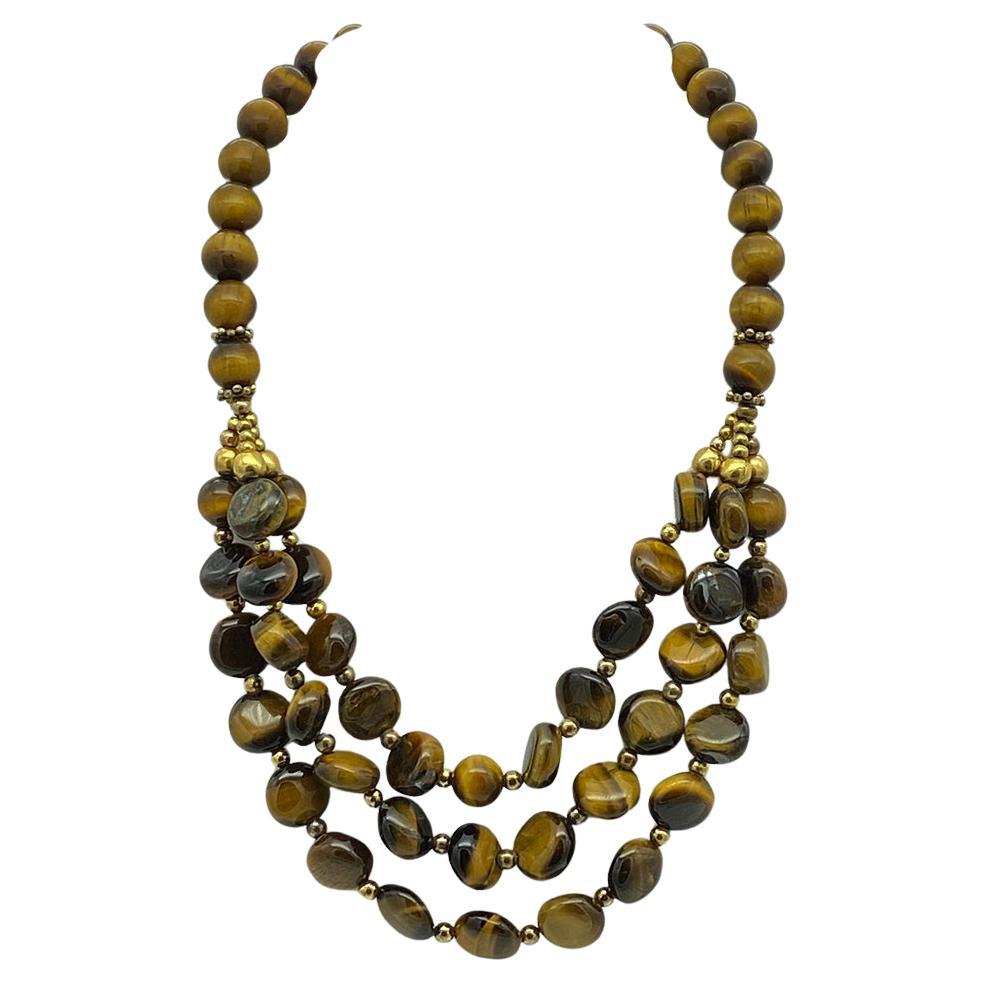 This is a Tiger's Eye gemstone bib necklace. It's an original work of Nouveau Boutique. There are triple strands of 12-14mm button shaped beads as bib and 10mm round beads for the rest of the necklace. It comes with a brass spring clasp with four